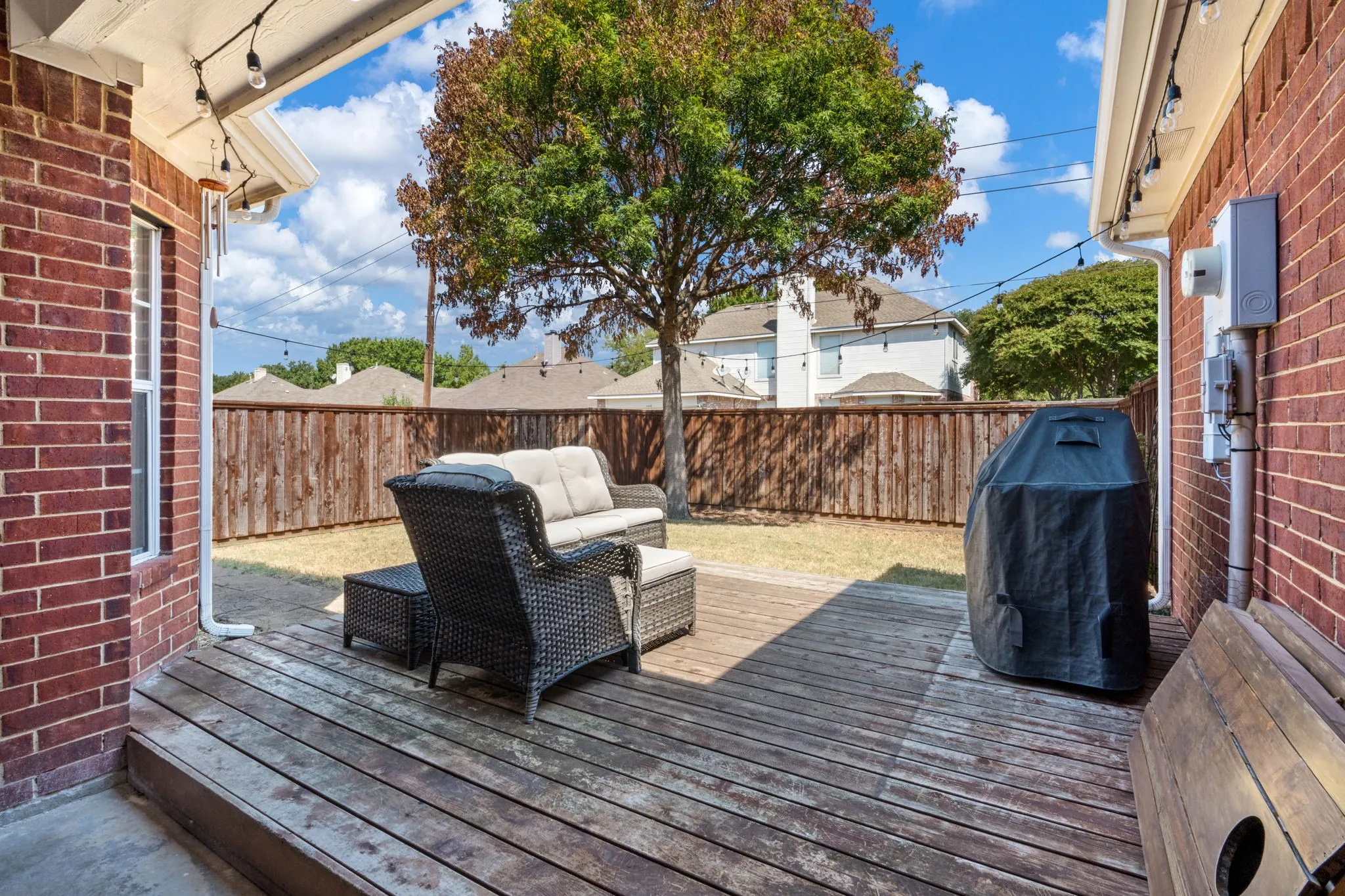 Wood deck patio with string lighting and brick exterior