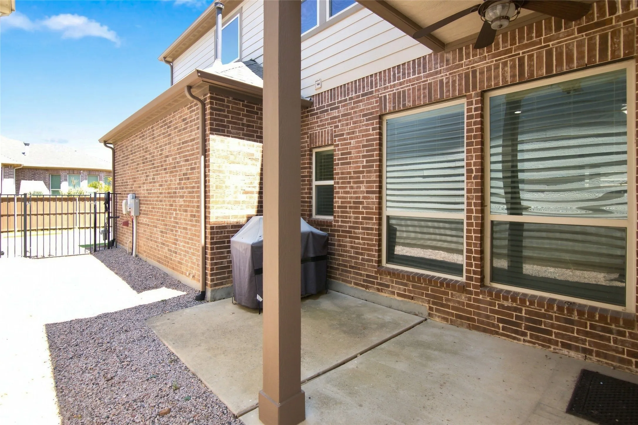 Brick exterior with covered patio, concrete flooring, and an outdoor ceiling fan