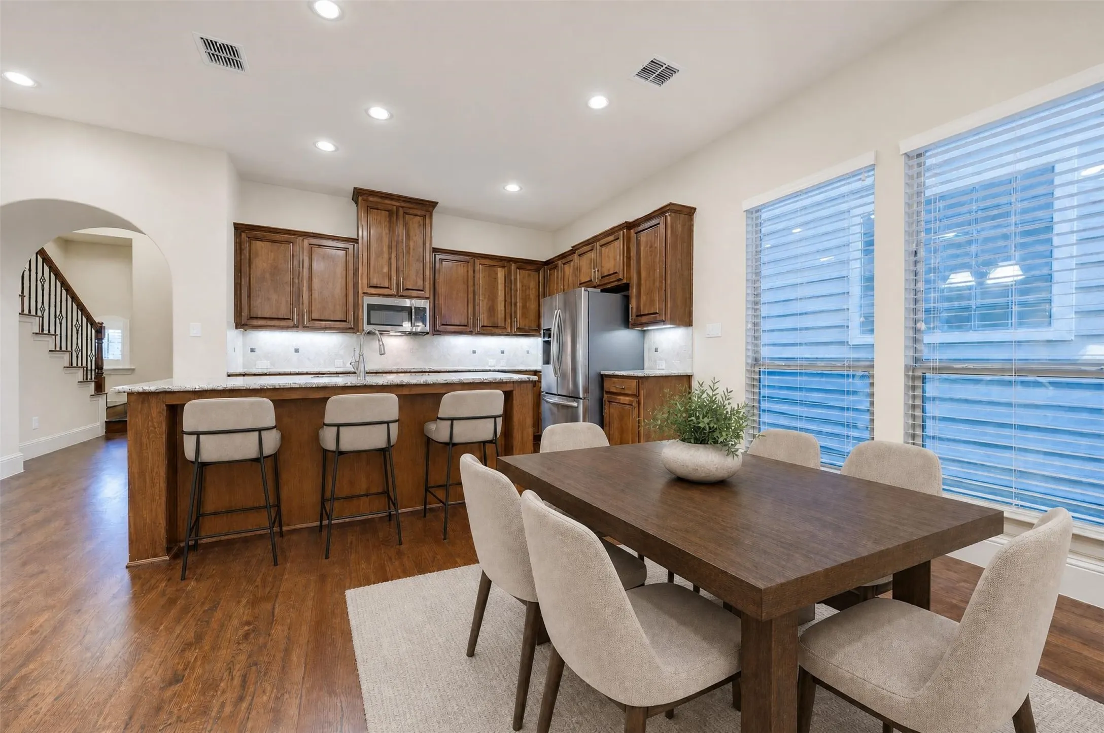 Kitchen featuring wood-finish cabinetry, stainless steel appliances, and a light-toned stone backsplash