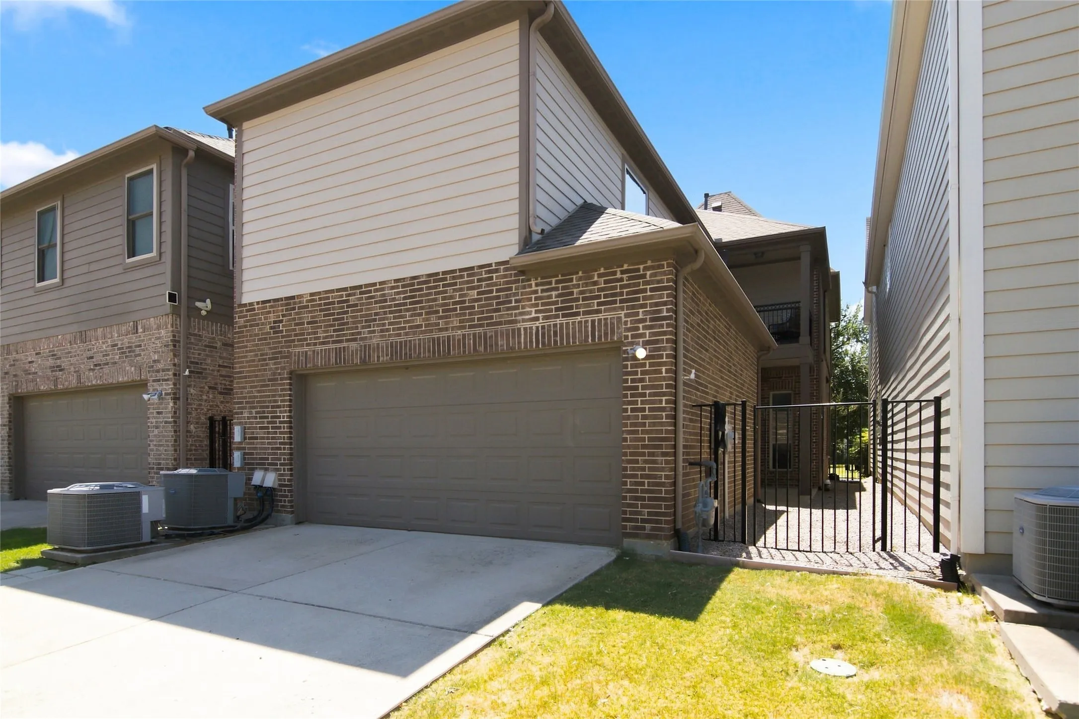 Two-story exterior with brick and siding, featuring an attached garage, paved driveway, and a fenced side yard