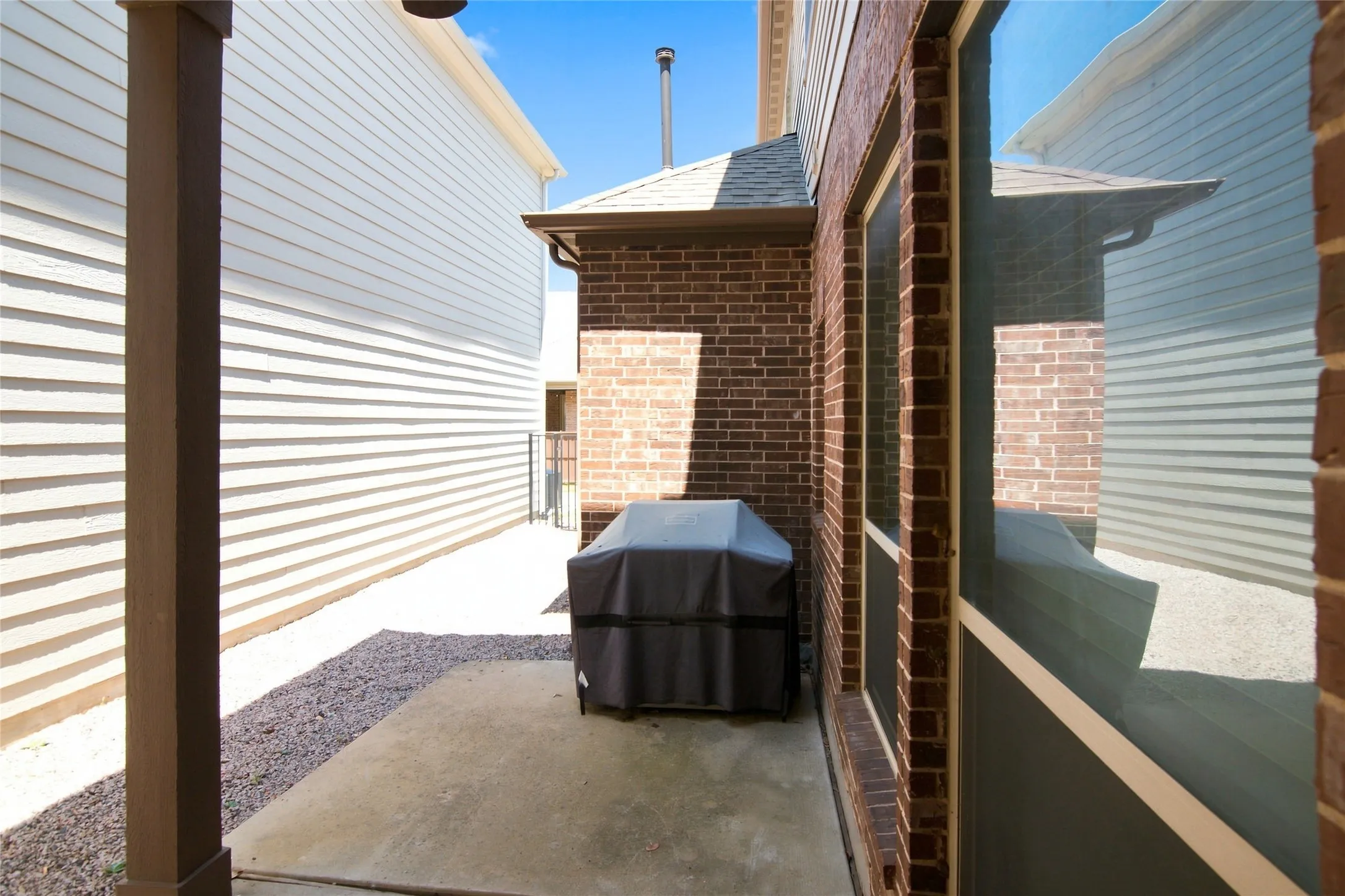Concrete patio area featuring a brick exterior and large glass door