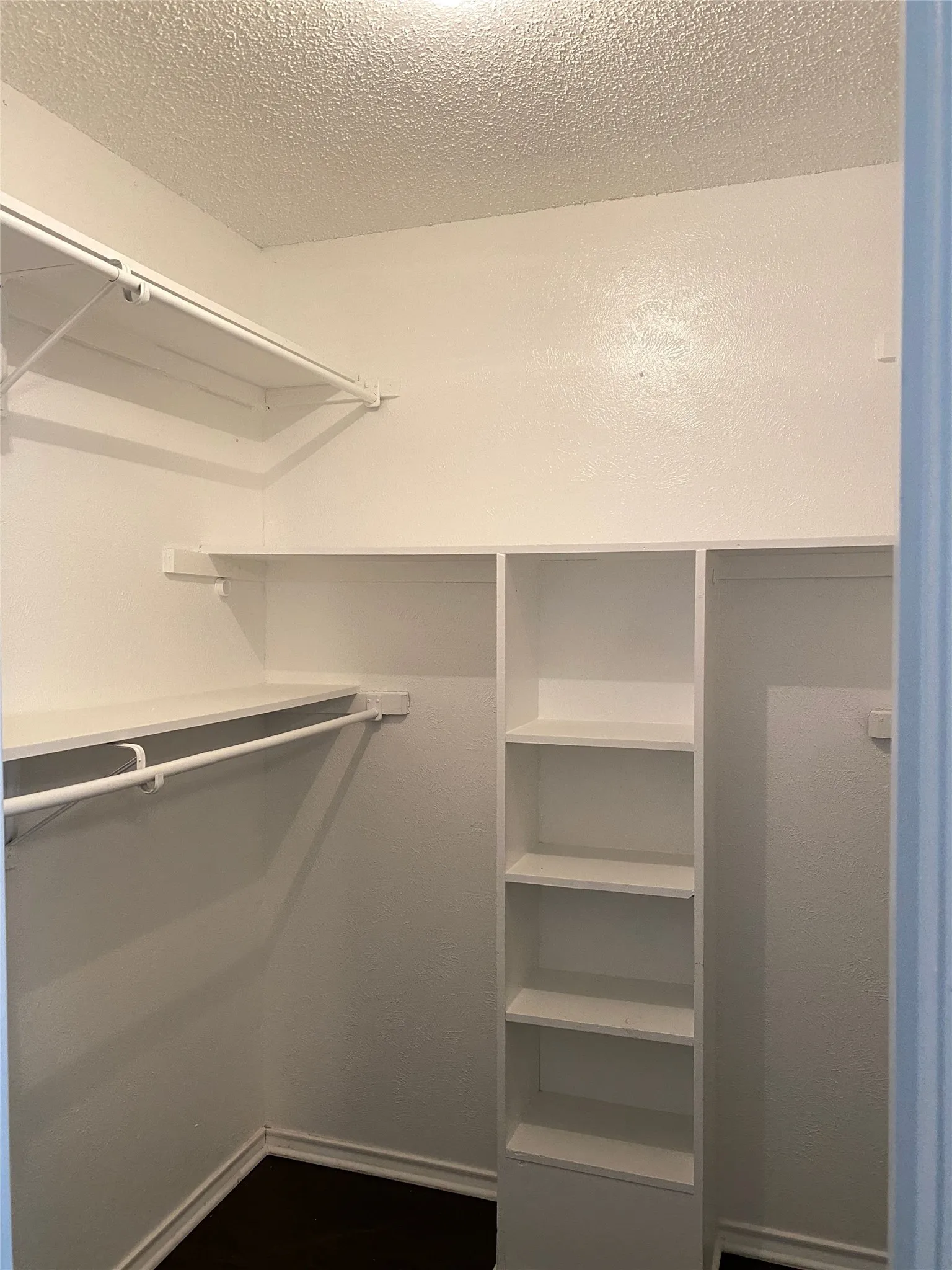White built-in shelving, white clothes rods, dark wood-finish flooring