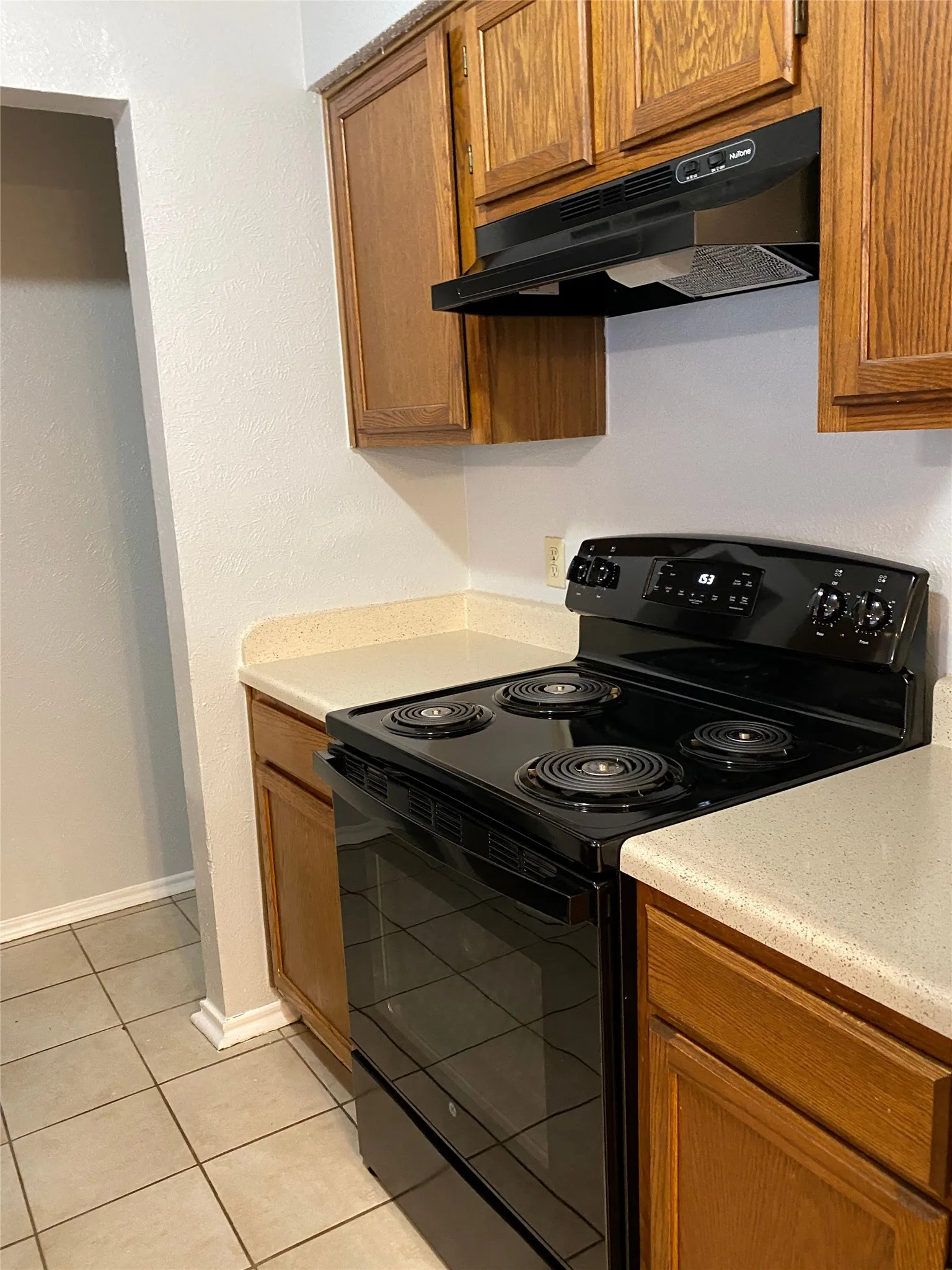 Wood-finish cabinetry paired with light-toned countertops and a black range