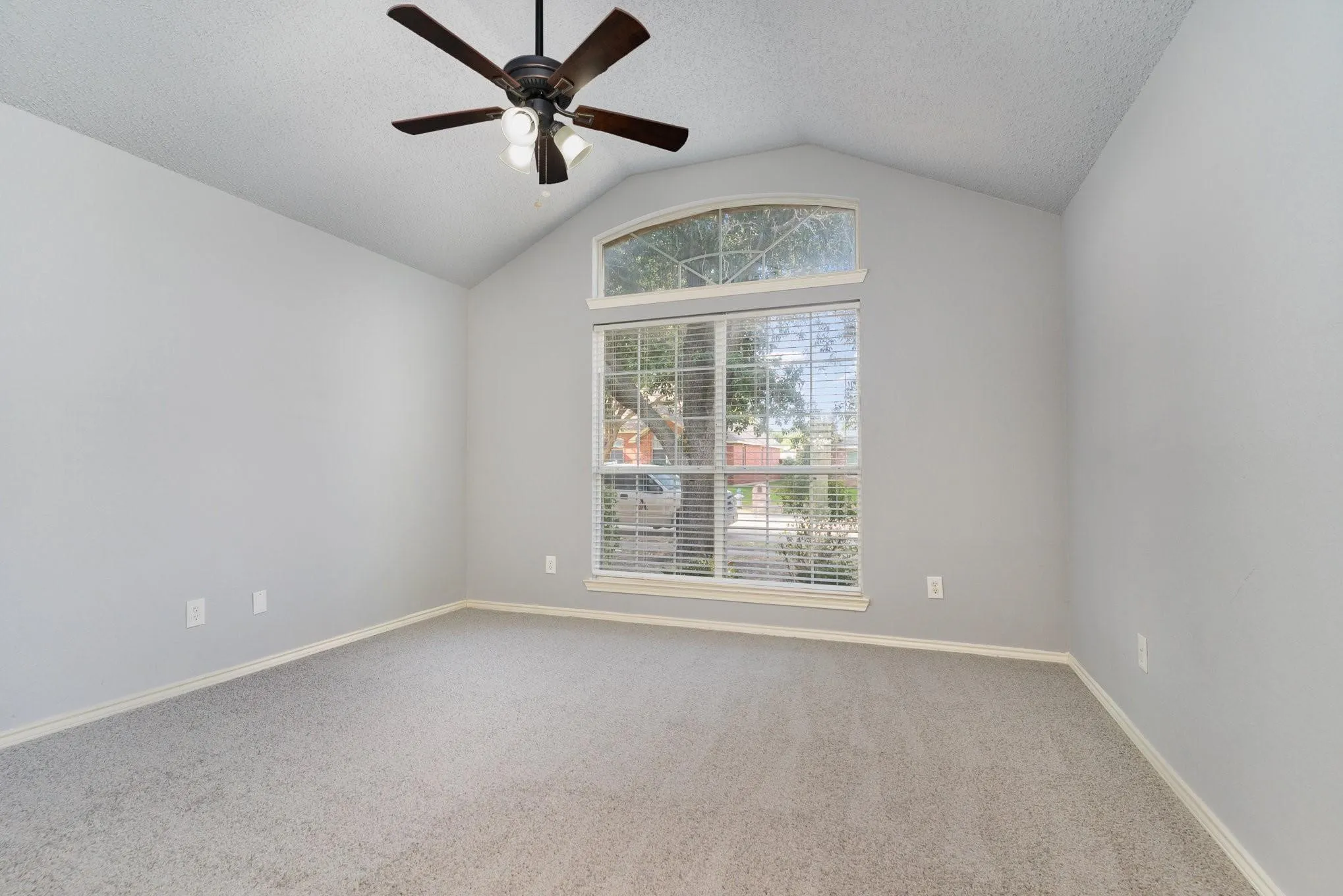 Vaulted ceiling with a ceiling fan, arched transom window, and carpeted flooring