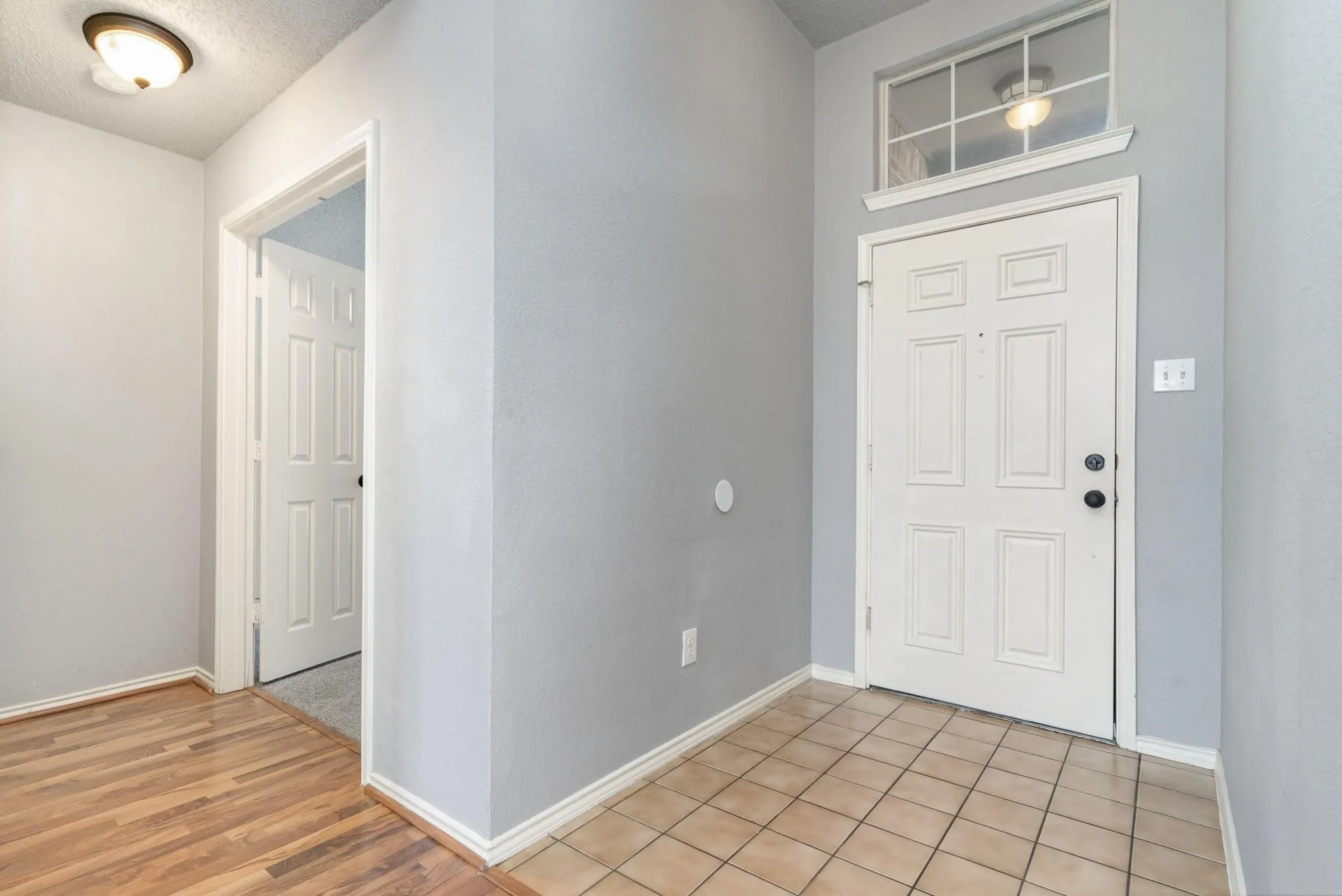 Entryway featuring a paneled door with transom window, tile flooring, and a flush mount light fixture