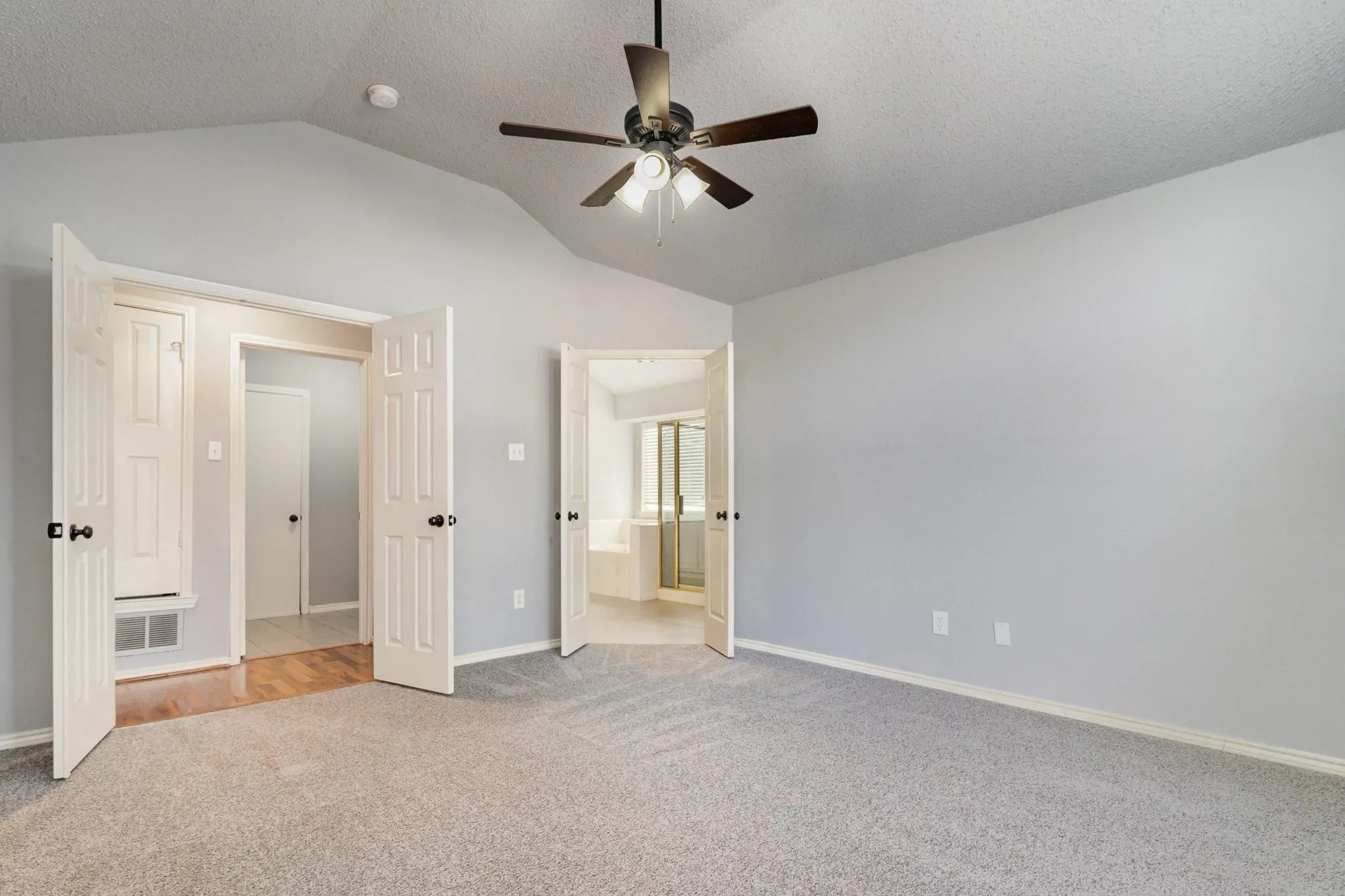 Vaulted ceiling, ceiling fan with integrated lighting, carpeted flooring, paneled doors, and light gray wall paint