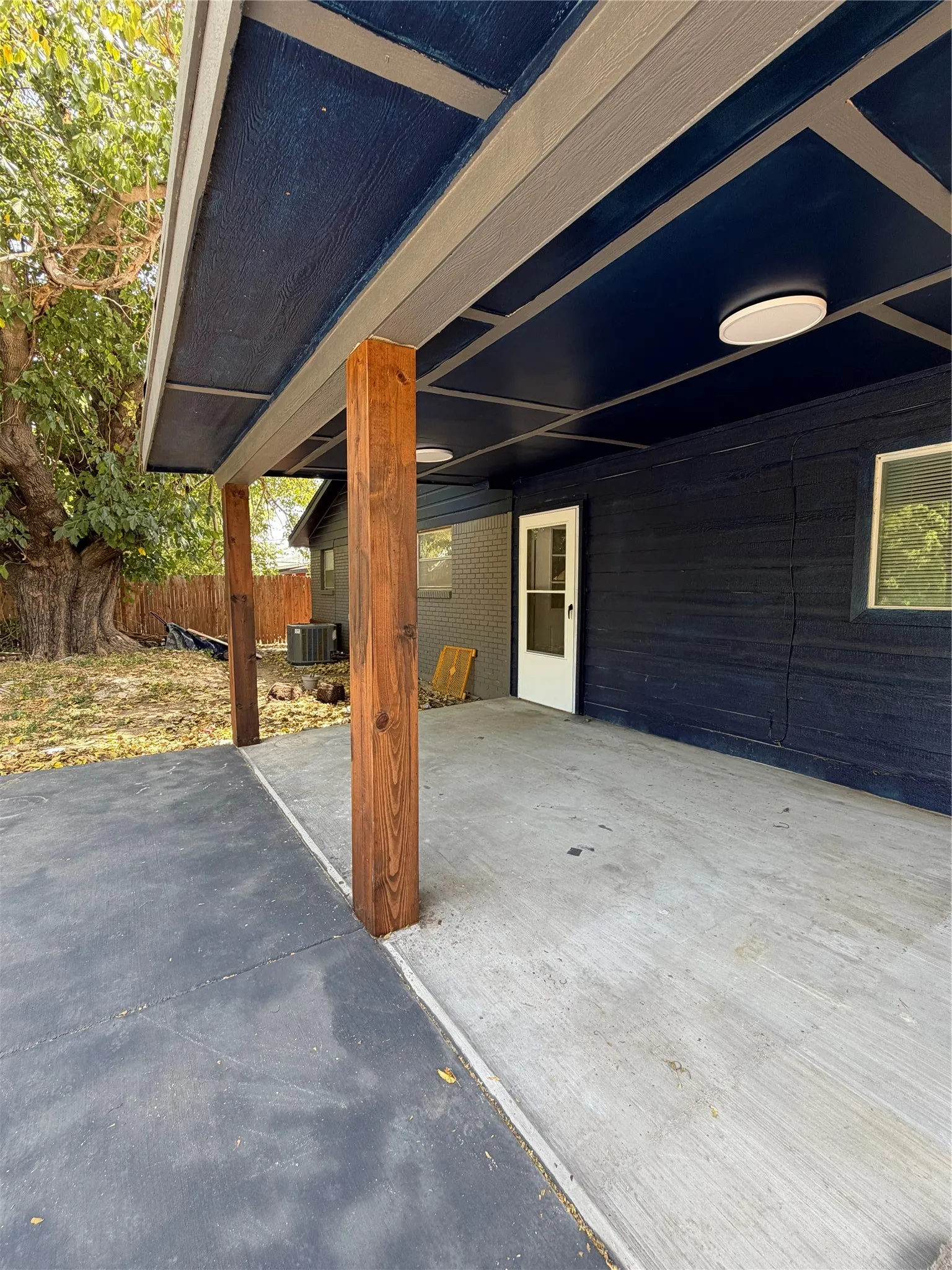 Covered patio featuring wood posts, concrete flooring, and flush-mount lighting