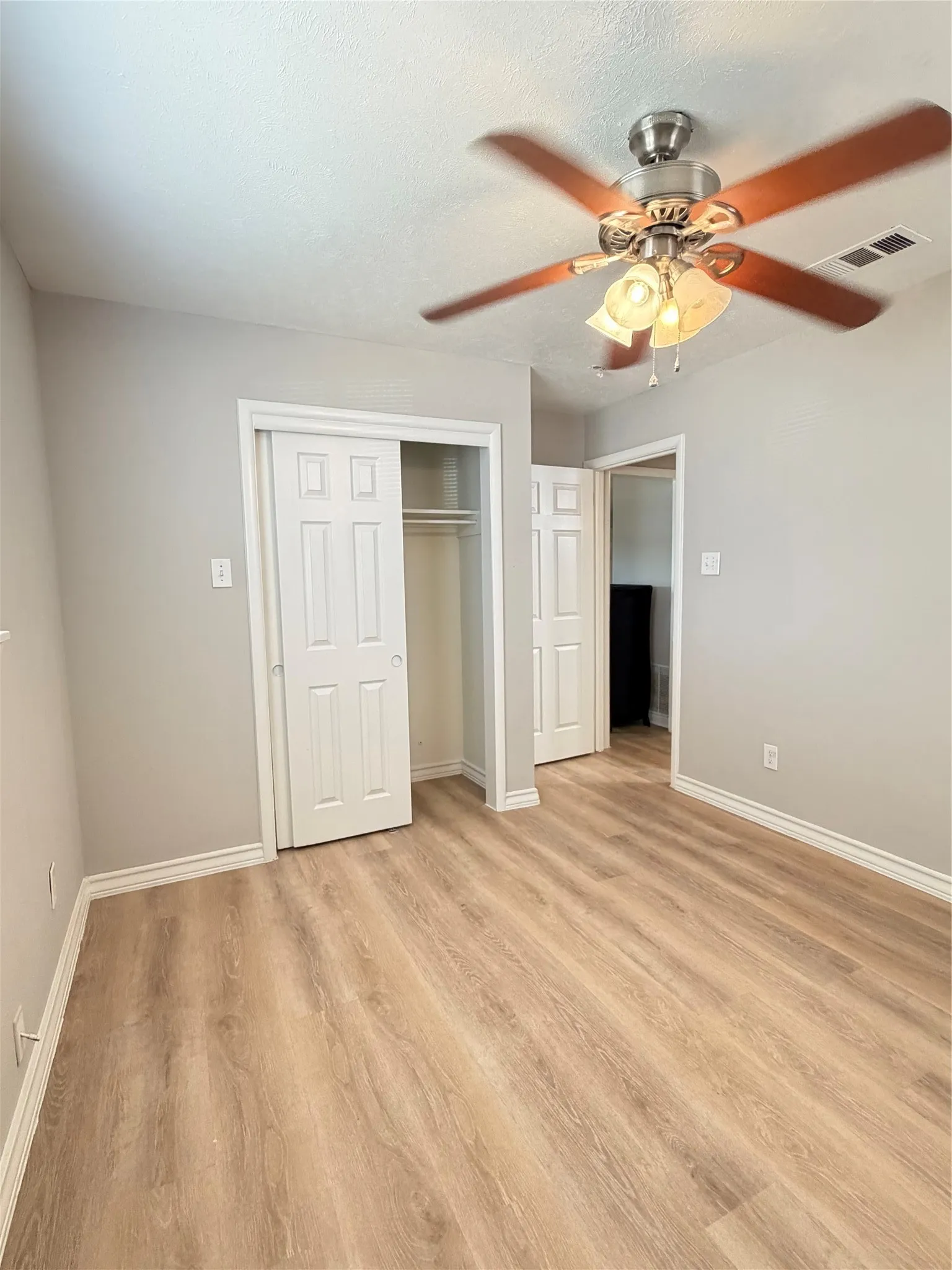 Wood-finish flooring, neutral wall tones, and overhead ceiling fan with integrated lighting