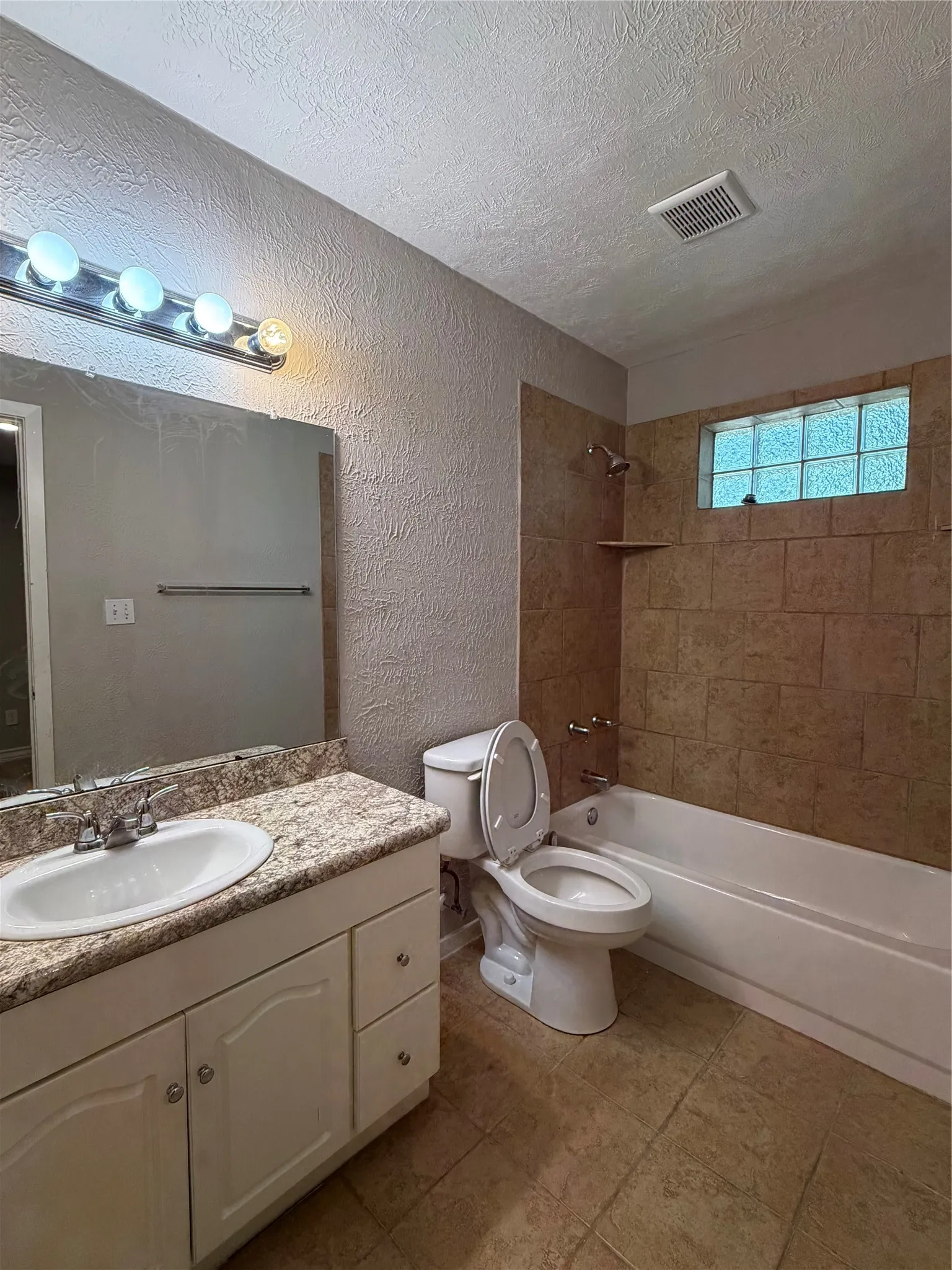 White vanity with integrated sink, patterned countertop, and mirrored wall