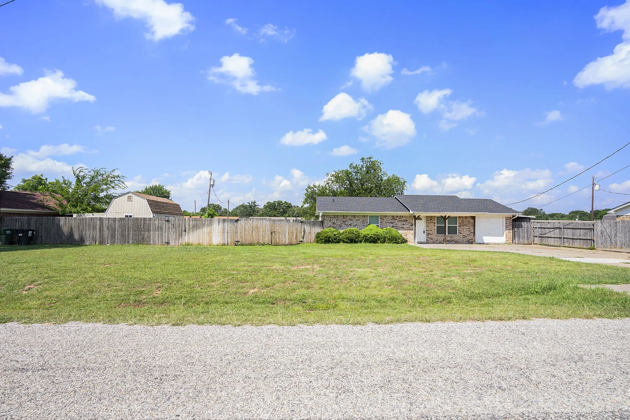 Brick exterior, attached garage, and a fenced yard with a manicured lawn