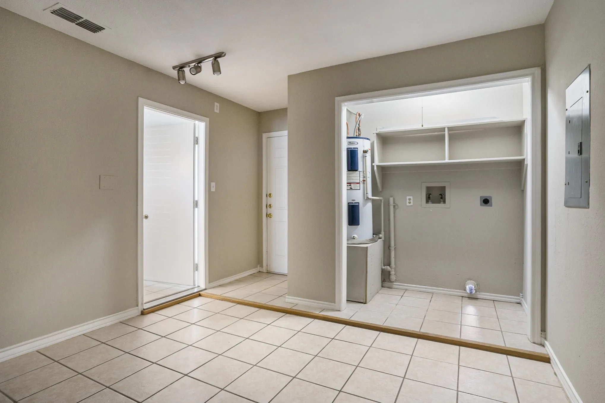 Utility area featuring a water heater, built-in shelving, track lighting, and tile flooring