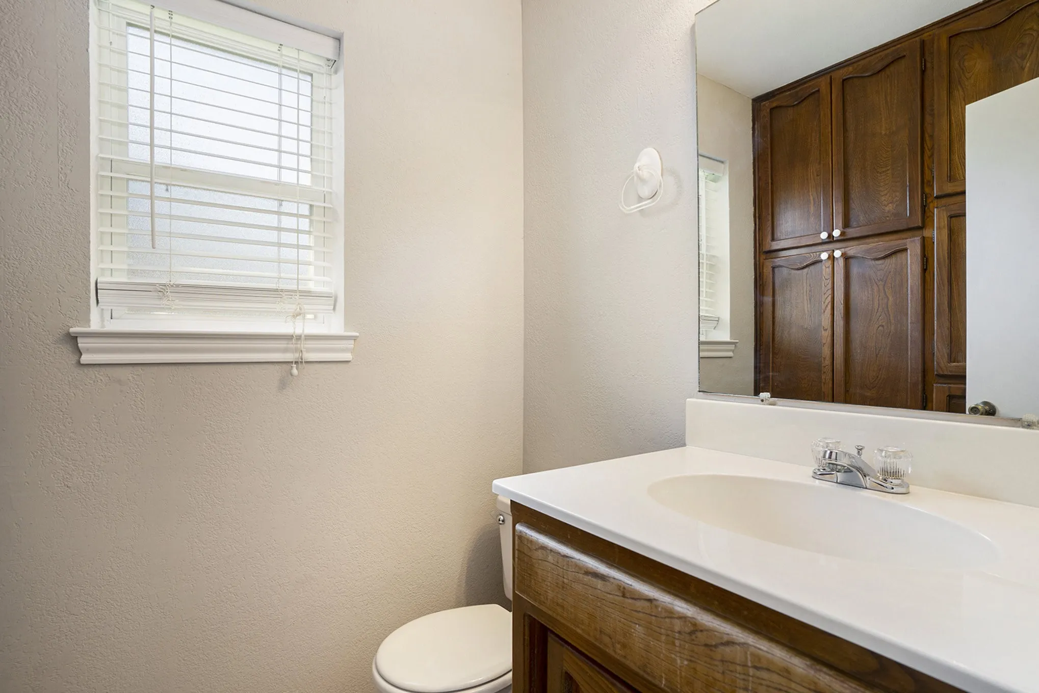 Built-in vanity with wood-finish cabinetry, a white countertop, and an integrated sink