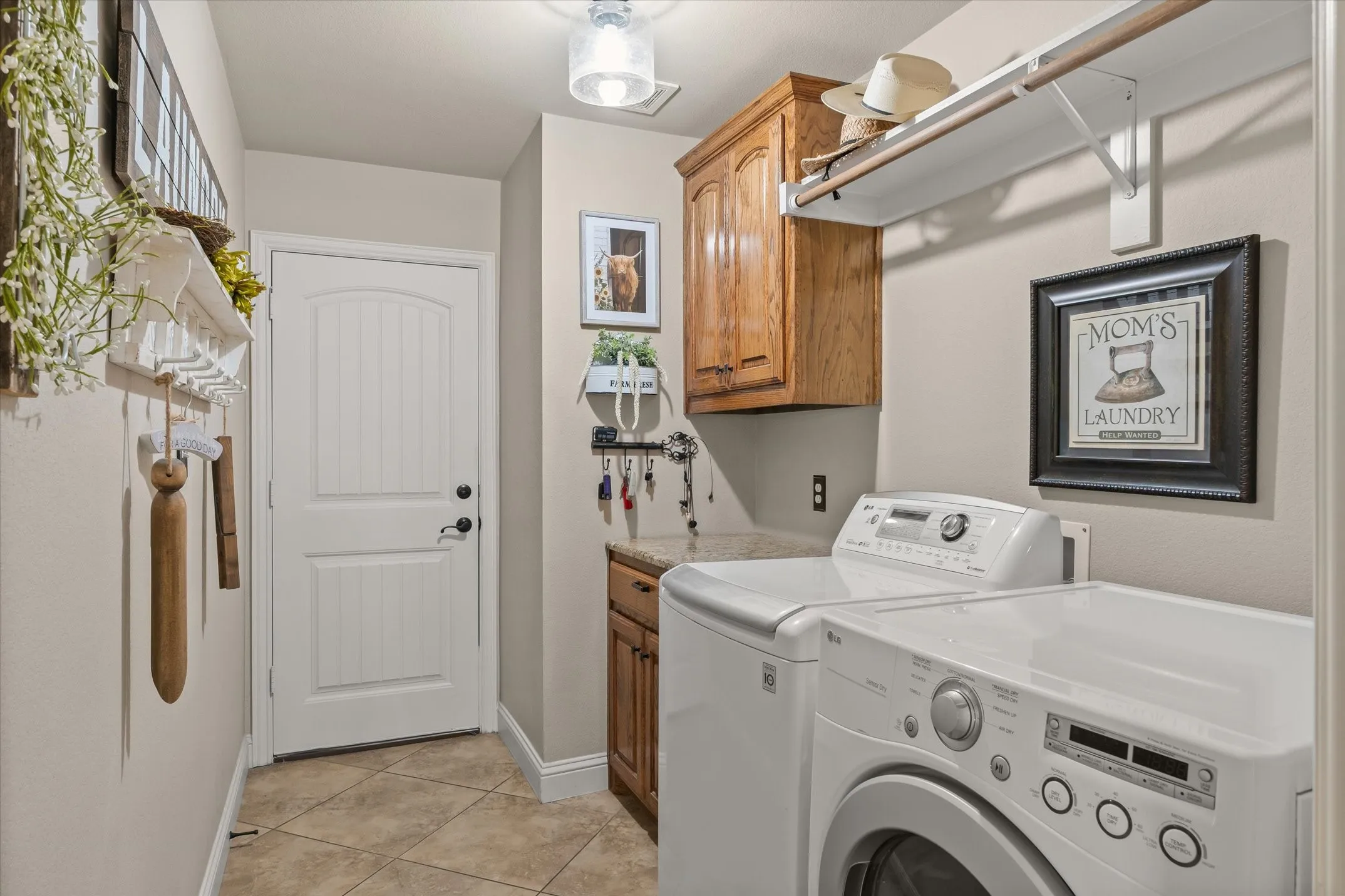 Laundry area with tile flooring, wood-finish cabinetry, and a countertop surface