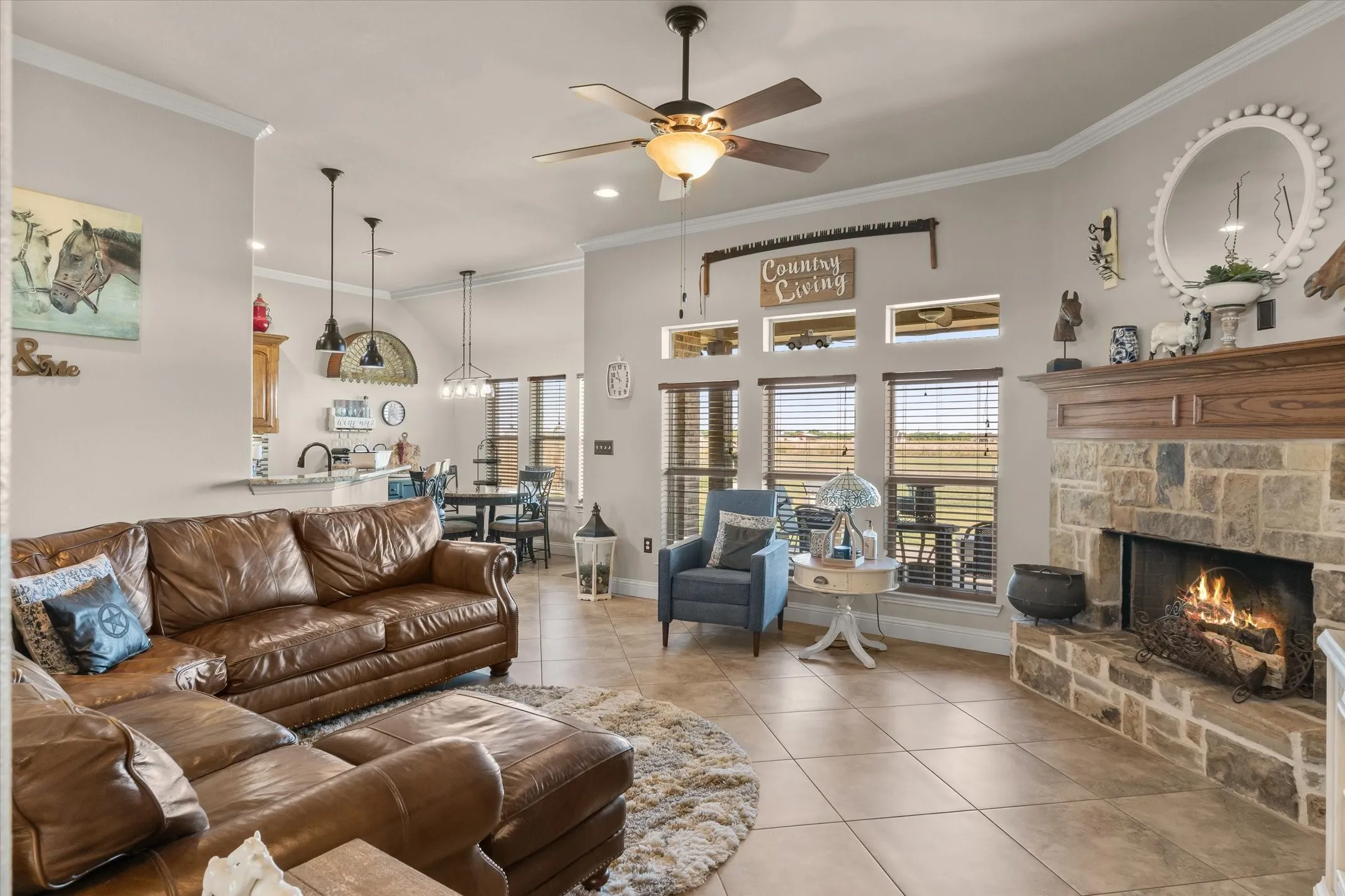 Spacious living area featuring a stone fireplace with a wood mantel, crown molding, and tile flooring