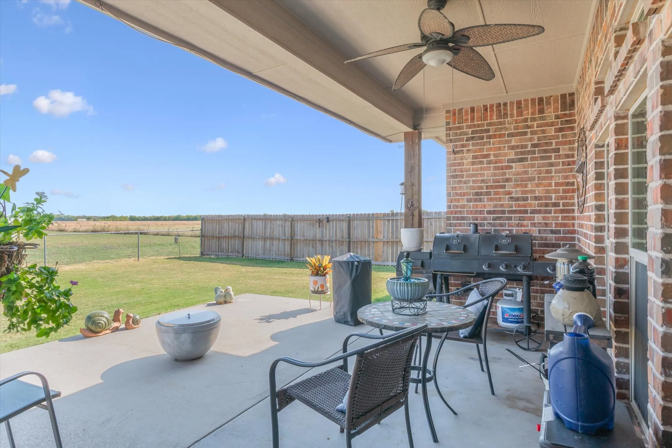 Covered patio with a ceiling fan, concrete flooring, and a brick exterior wall
