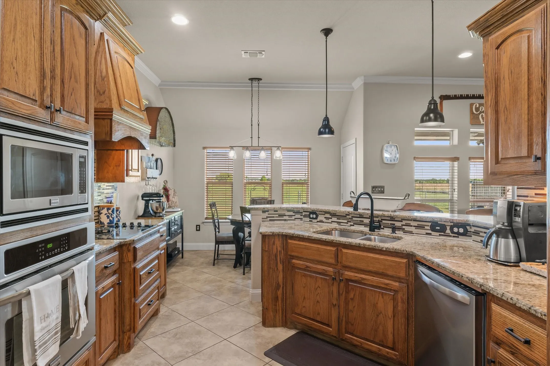 Kitchen featuring wood cabinetry, stainless steel appliances, a double basin sink with a matte black faucet, and a stone-finish countertop