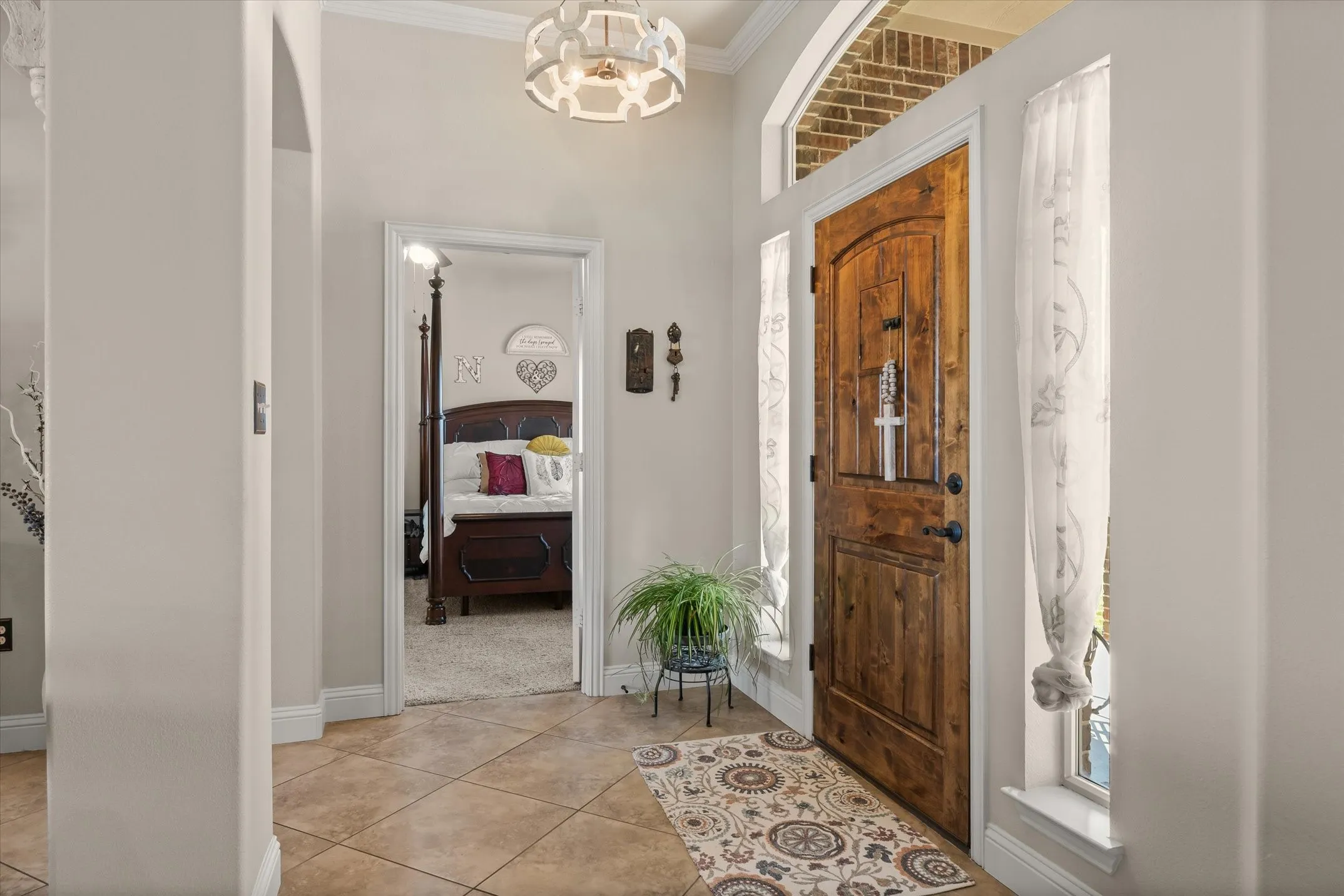 Arched wood-panel entry door with sidelight windows, transom window, and tile flooring