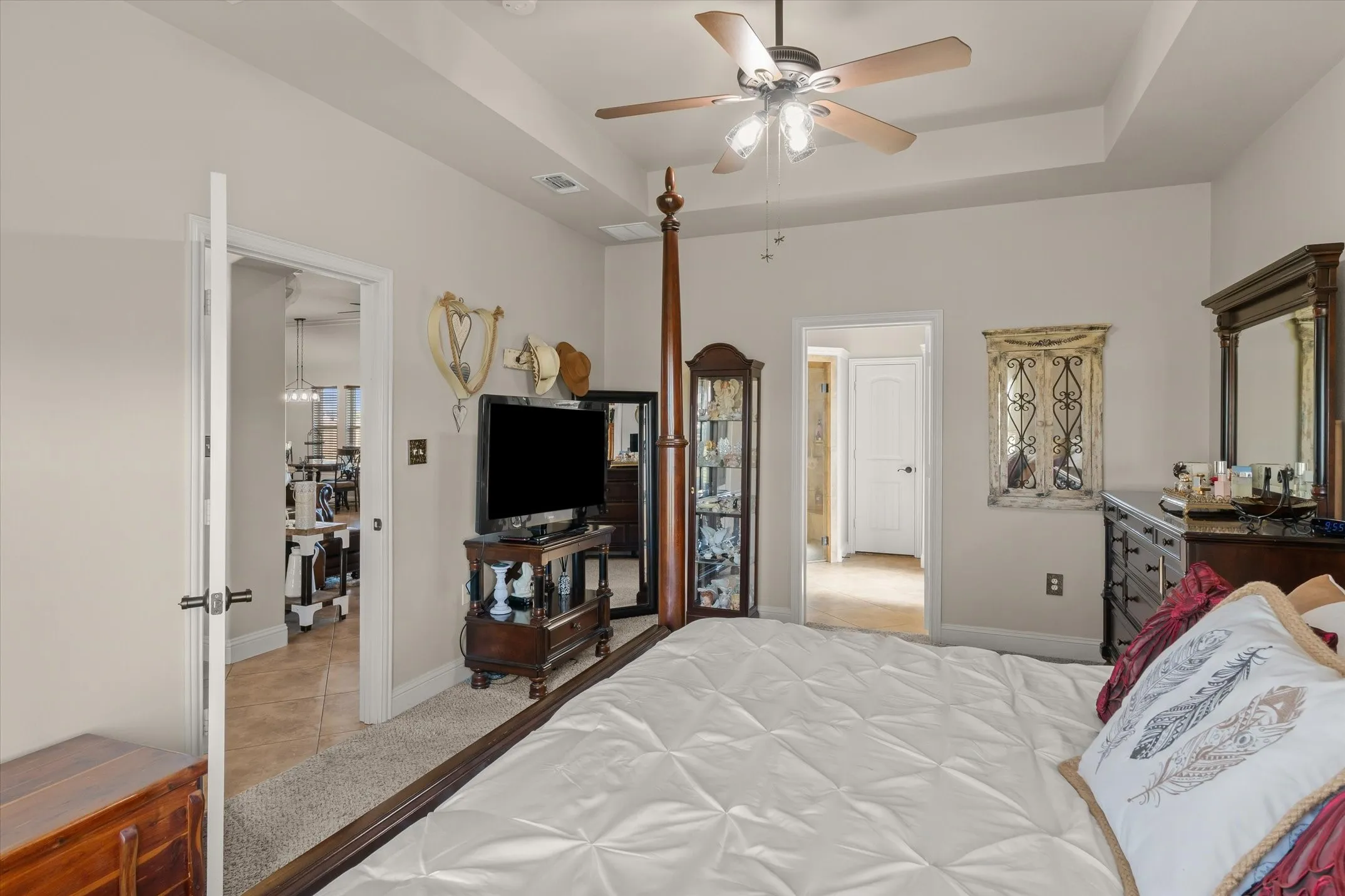 Tray ceiling with a ceiling fan, light-colored carpeting, and neutral wall paint