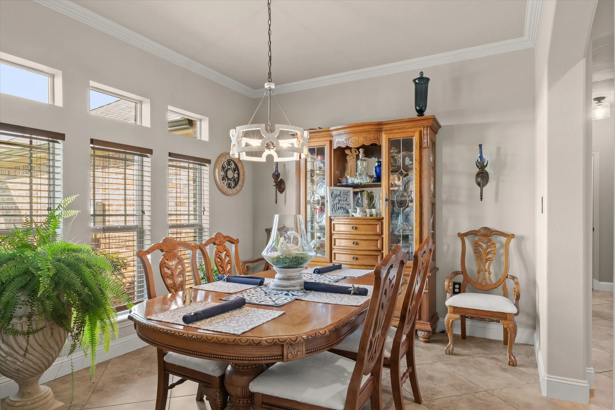 Tile flooring throughout, crown molding, multiple transom windows, decorative wall sconces, and a contemporary chandelier