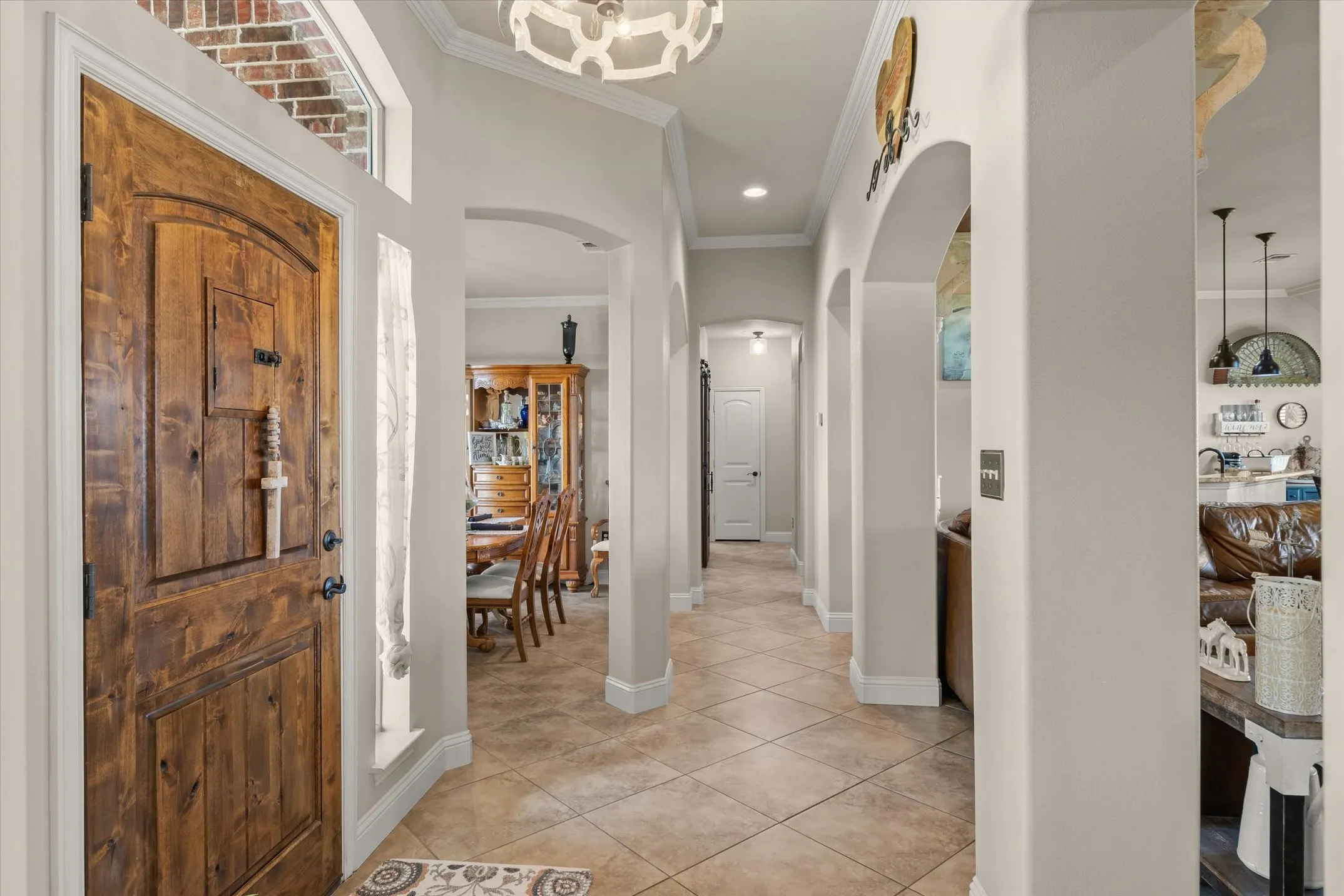Solid wood entry door with transom window, tile flooring, arched doorways, crown molding, and recessed lighting