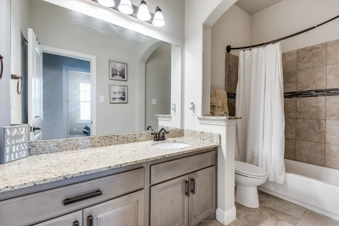 Vanity with a granite countertop, undermount sink, and dark bronze faucet