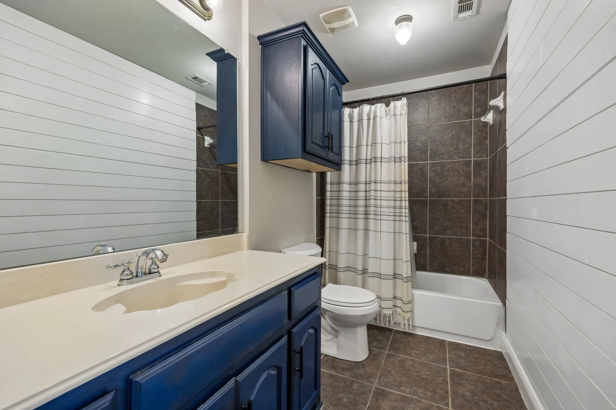 A Full Bath for the Upstairs Bedrooms - This secondary bath combines a tub-and-shower configuration with generous vanity space and additional cabinetry, creating practical storage and an easy everyday setup.