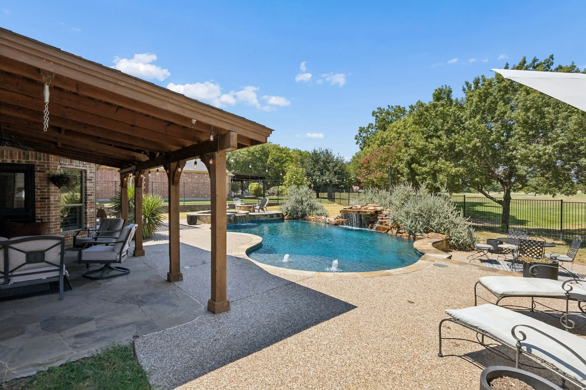 Poolside Living with a Golf Course Backdrop - The pool, covered patio and open-air seating areas come together in a backyard designed for entertaining, with mature trees and the golf course extending beyond the fence.