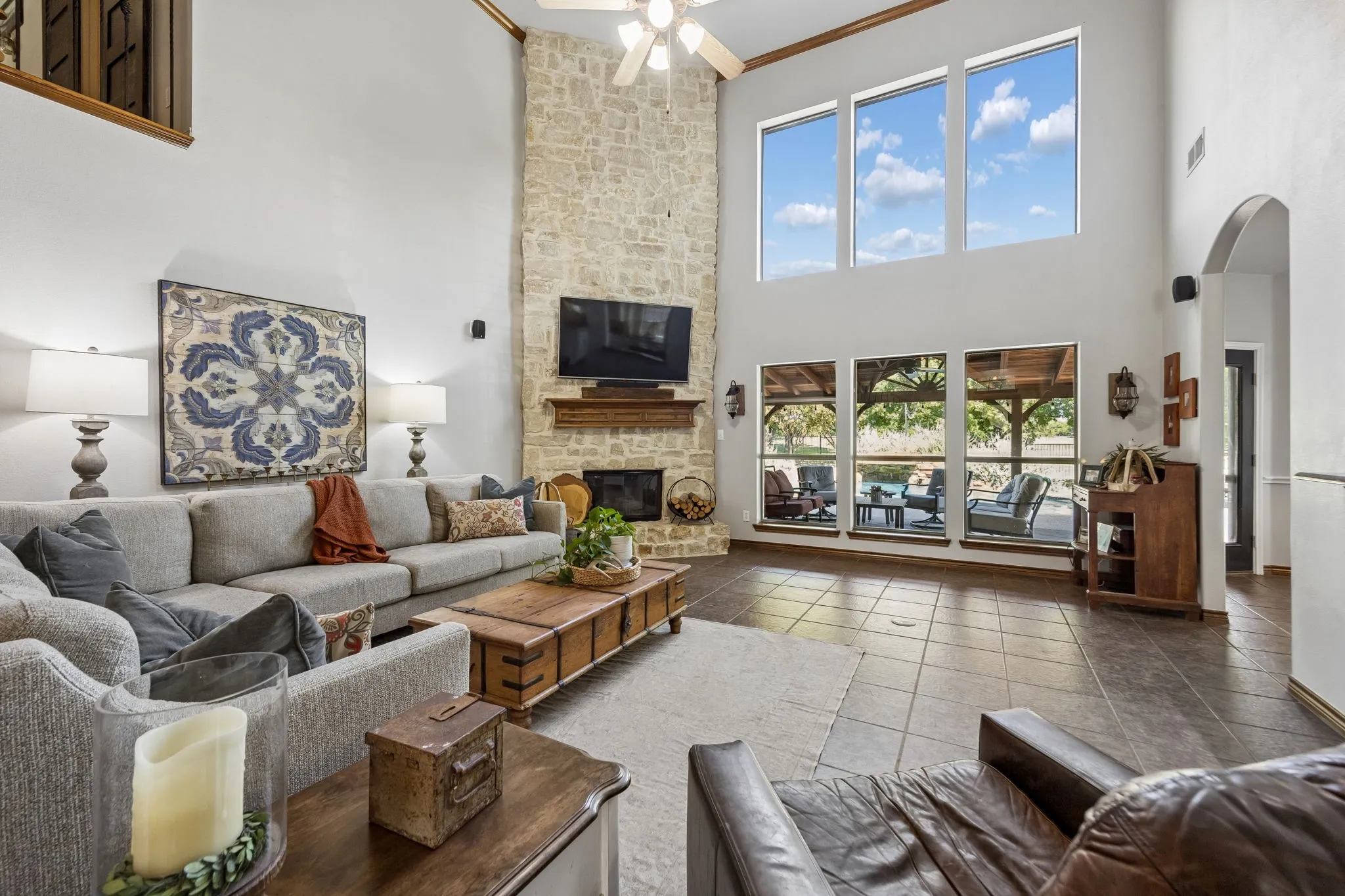 A Fireplace Built for the Room - Soaring ceilings and a dramatic floor-to-ceiling stone fireplace with a raised hearth anchor the spacious family room, while the open staircase and iron balusters add architectural interest overhead.