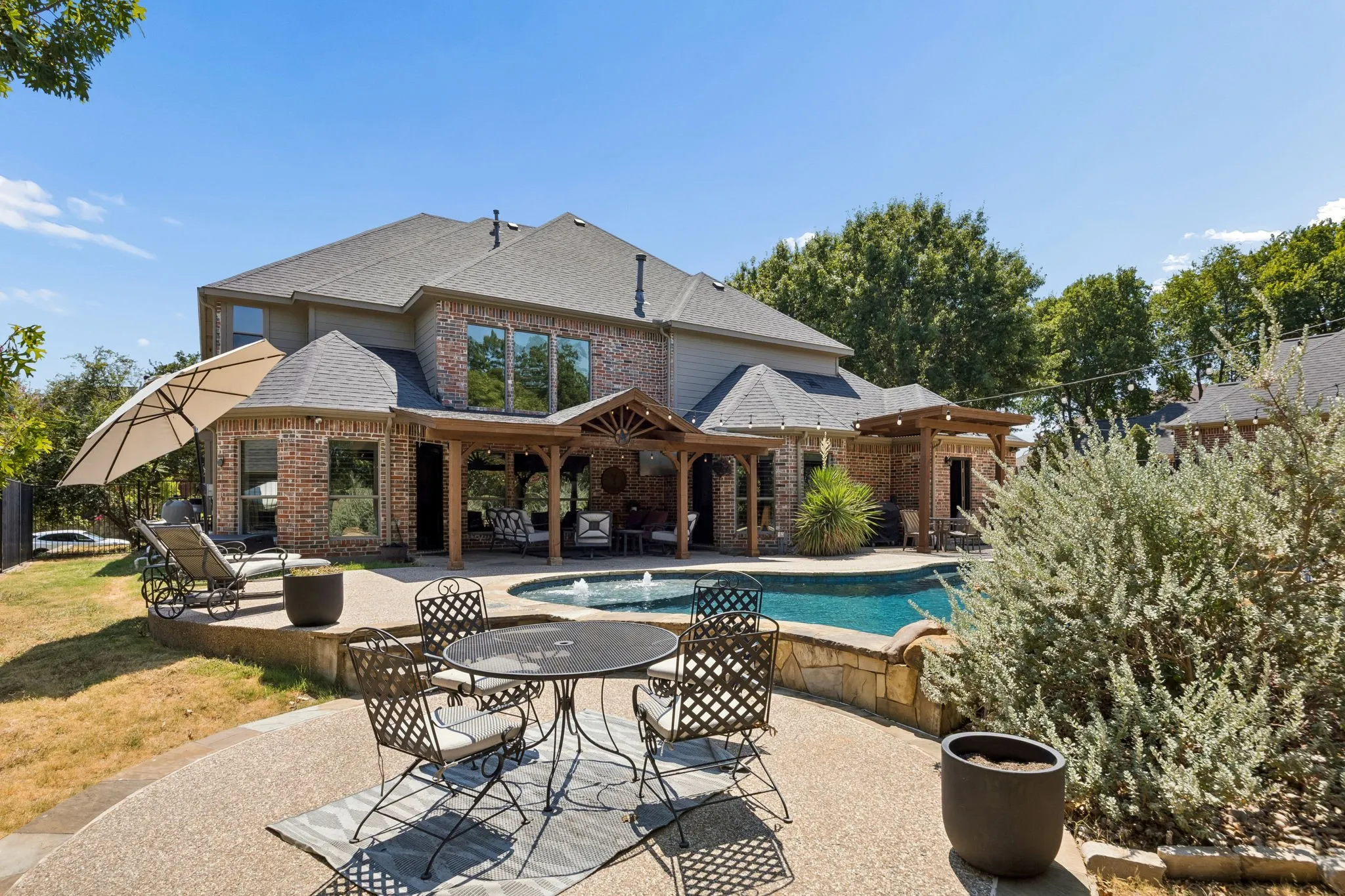 Poolside Living with a Golf Course Backdrop - The pool, covered patio and open-air seating areas come together in a backyard designed for entertaining, with mature trees and the golf course extending beyond the fence.