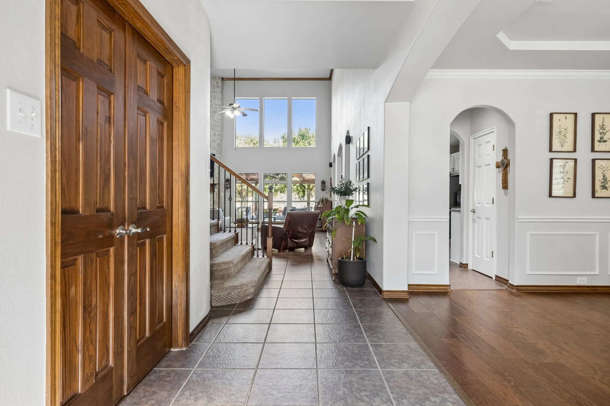 An Entry with a View - The foyer creates a long sightline toward the two-story family room and backyard beyond, with the formal dining room to one side and stained double doors opening to the private home office on the other.