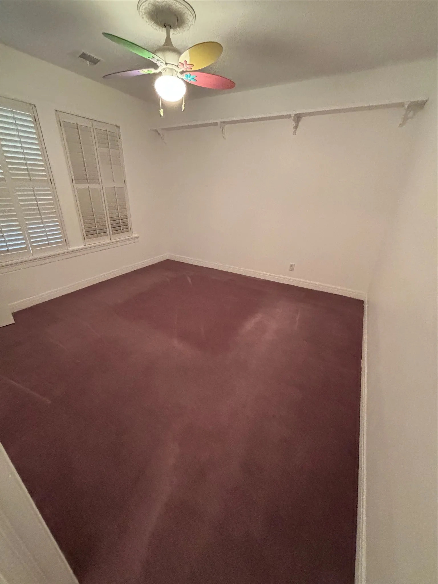 Empty room featuring carpet floors and a ceiling fan