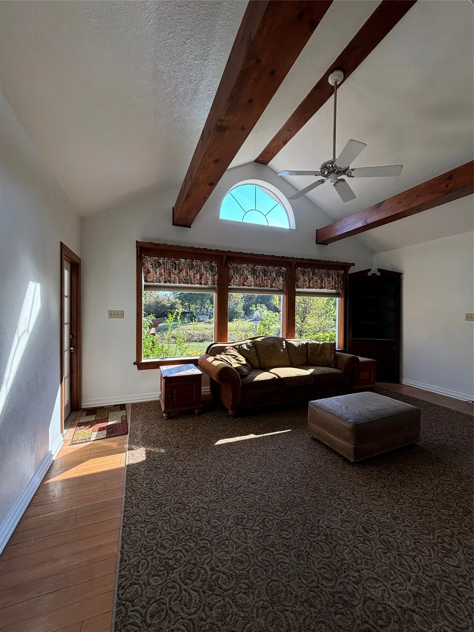 Living room featuring dark wood-type flooring, a ceiling fan, and a textured ceiling