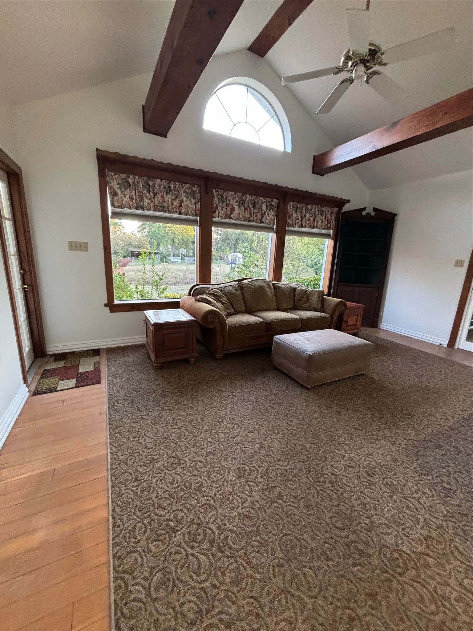 Living area with beamed ceiling, a ceiling fan, high vaulted ceiling, and light wood-style floors