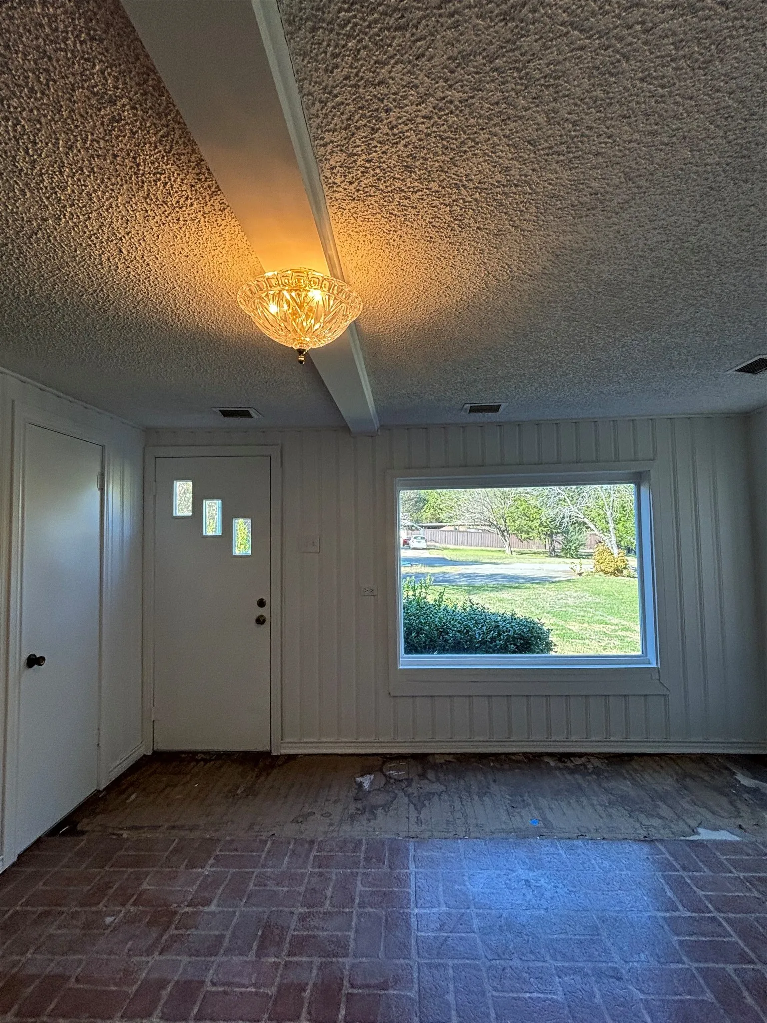 Entrance foyer with brick patterned floors and a textured ceiling