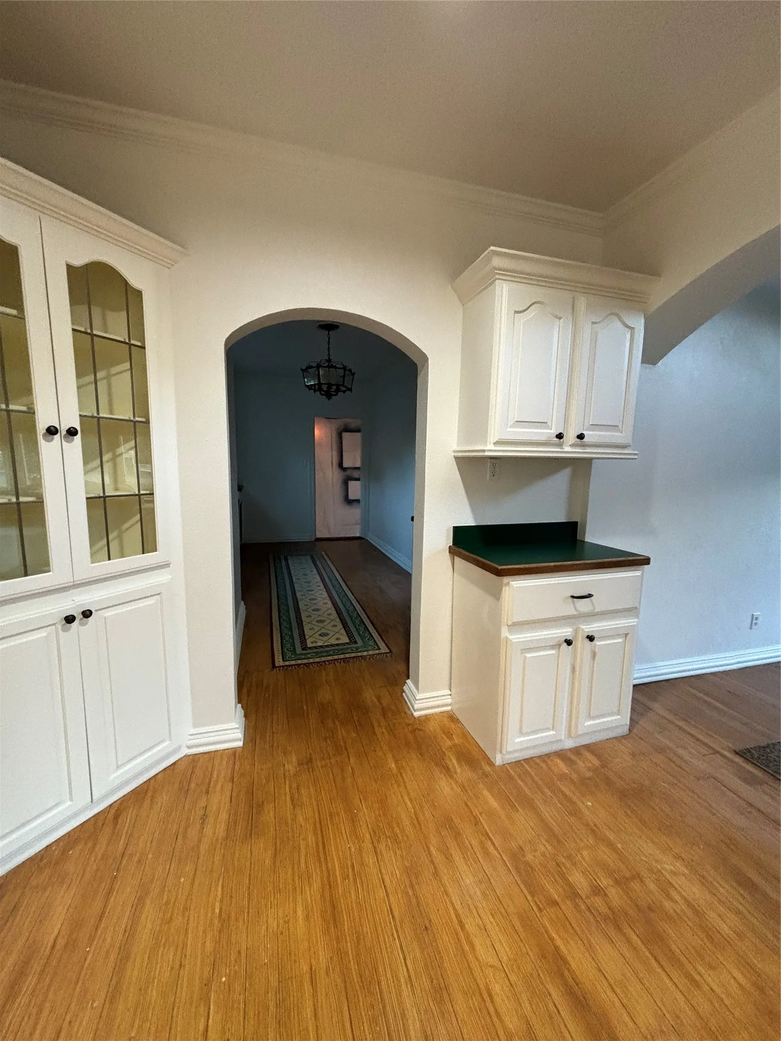 Hall with arched walkways, ornamental molding, and light wood-style flooring