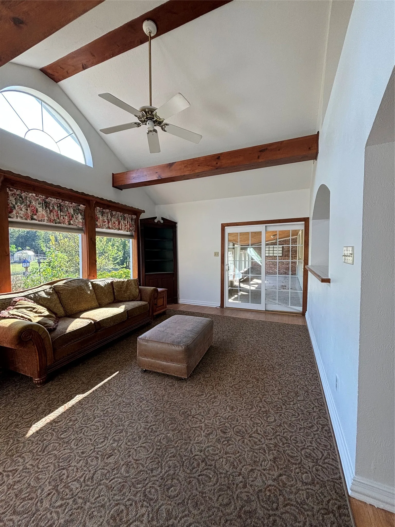 Living room with beam ceiling, carpet flooring, a ceiling fan, and high vaulted ceiling