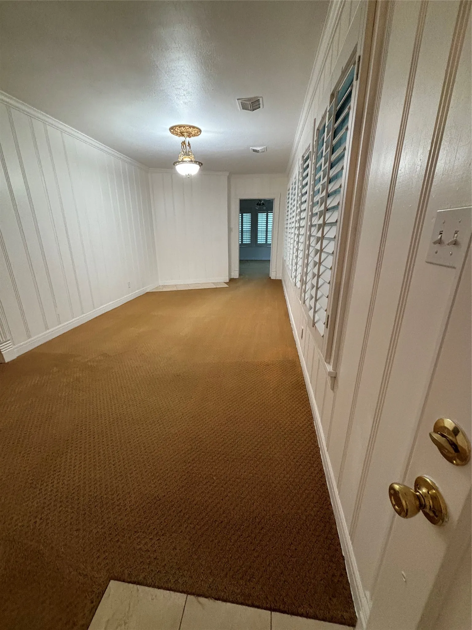 Hall with light colored carpet, crown molding, and a textured ceiling