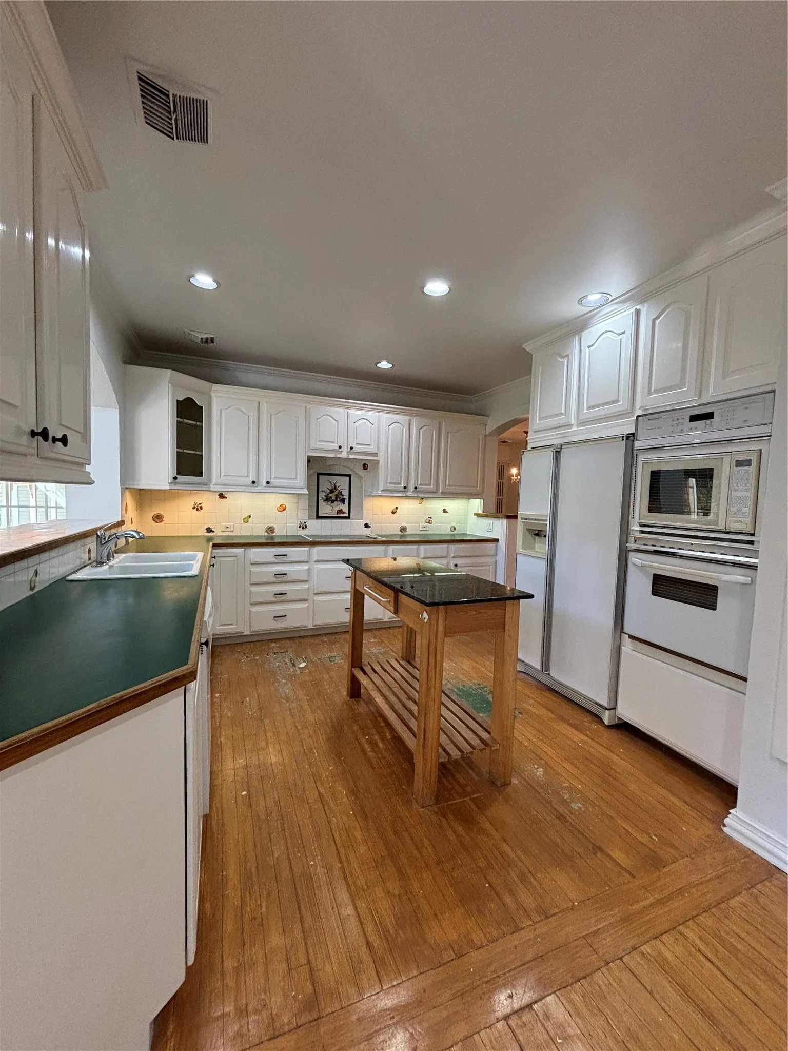 Kitchen featuring white cabinets, light wood-style floors, decorative backsplash, glass insert cabinets, and recessed lighting