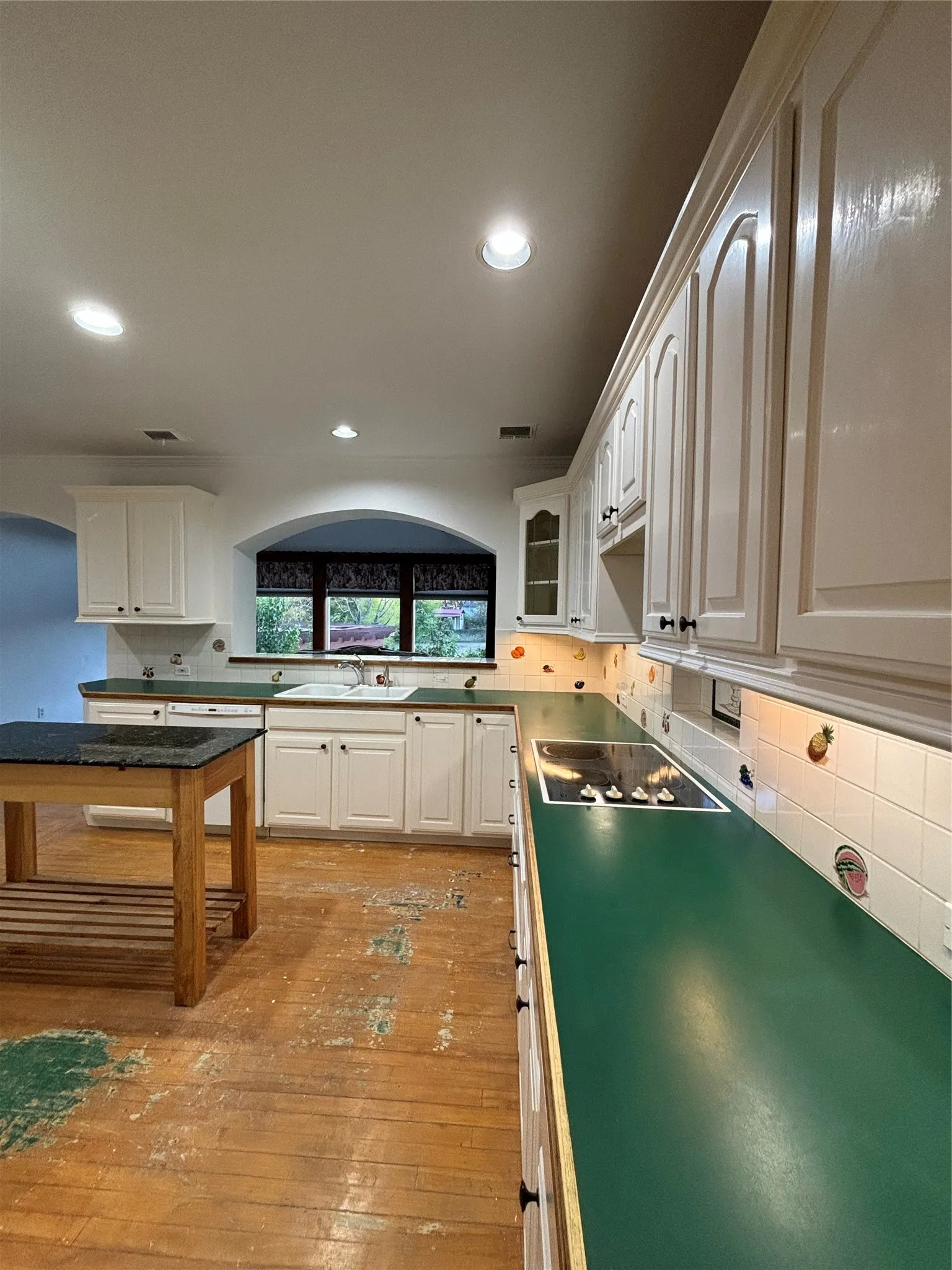 Kitchen featuring tasteful backsplash, light wood-style floors, glass insert cabinets, recessed lighting, and white cabinetry