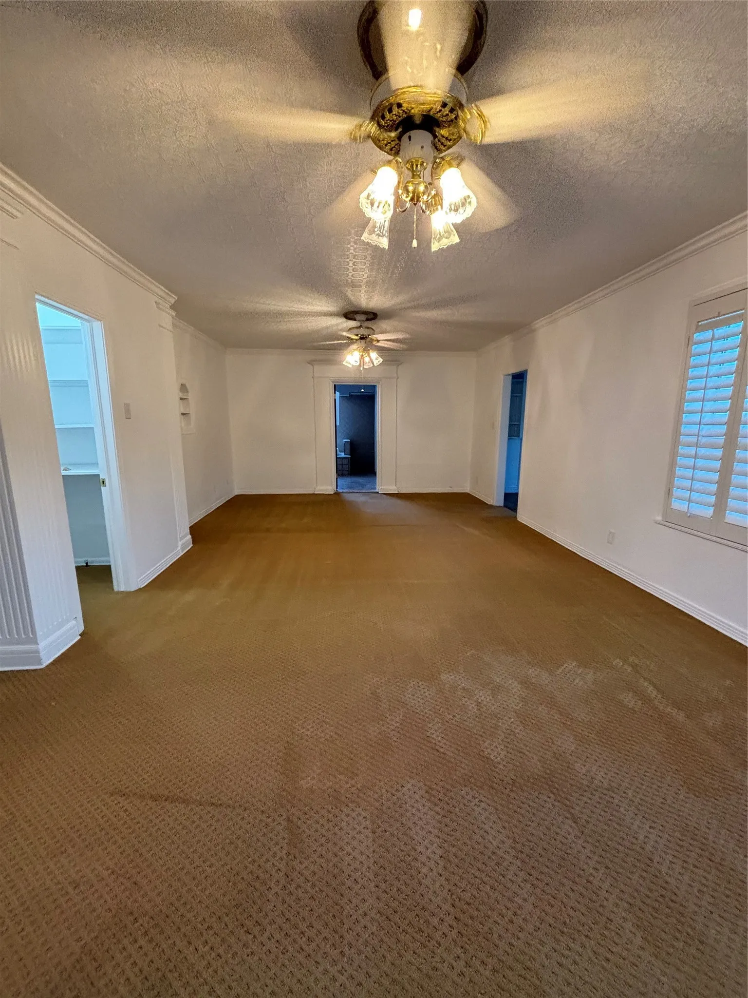 Carpeted empty room with a textured ceiling and ornamental molding