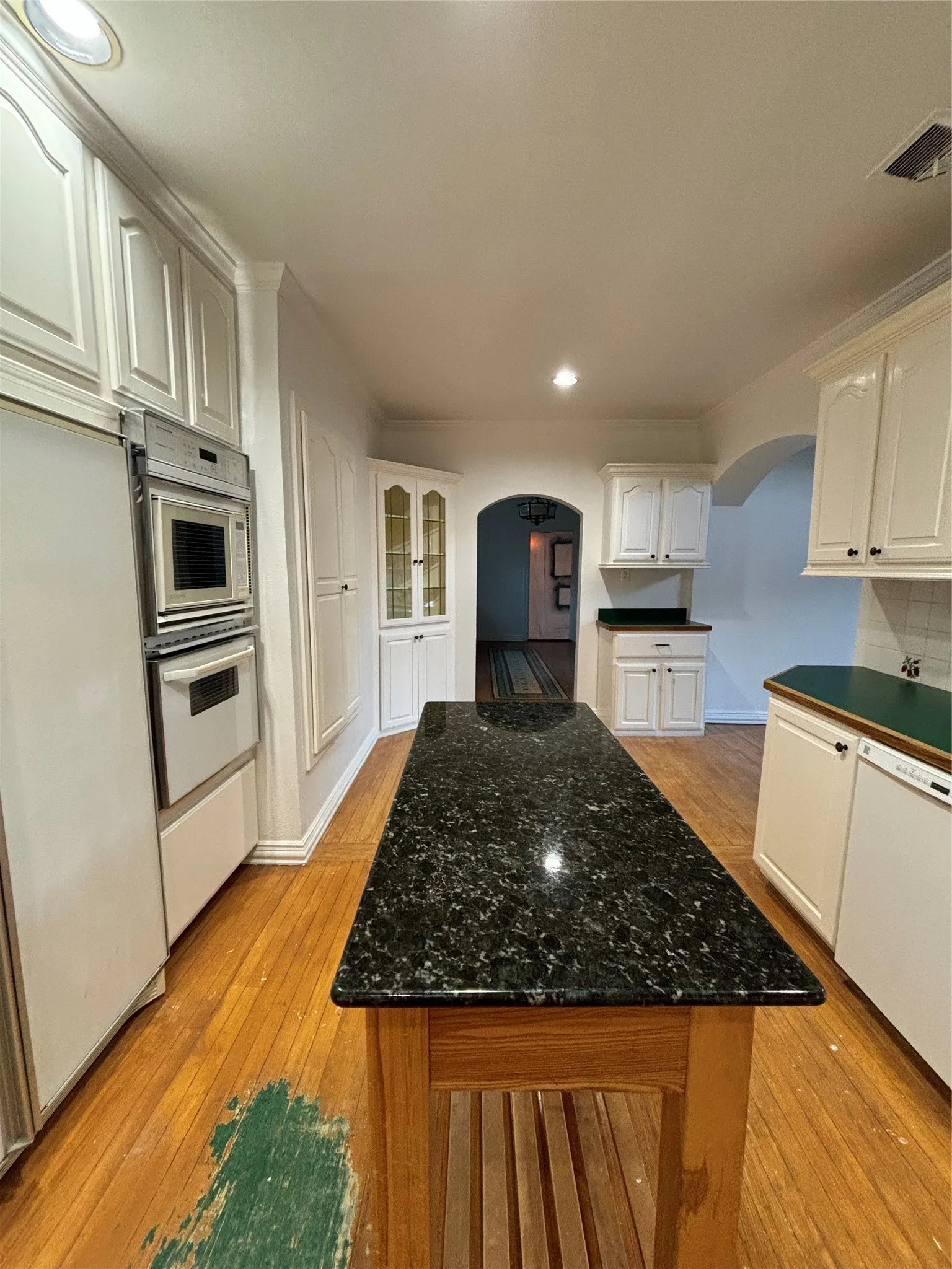 Kitchen with arched walkways, recessed lighting, light wood finished floors, dishwasher, and a center island