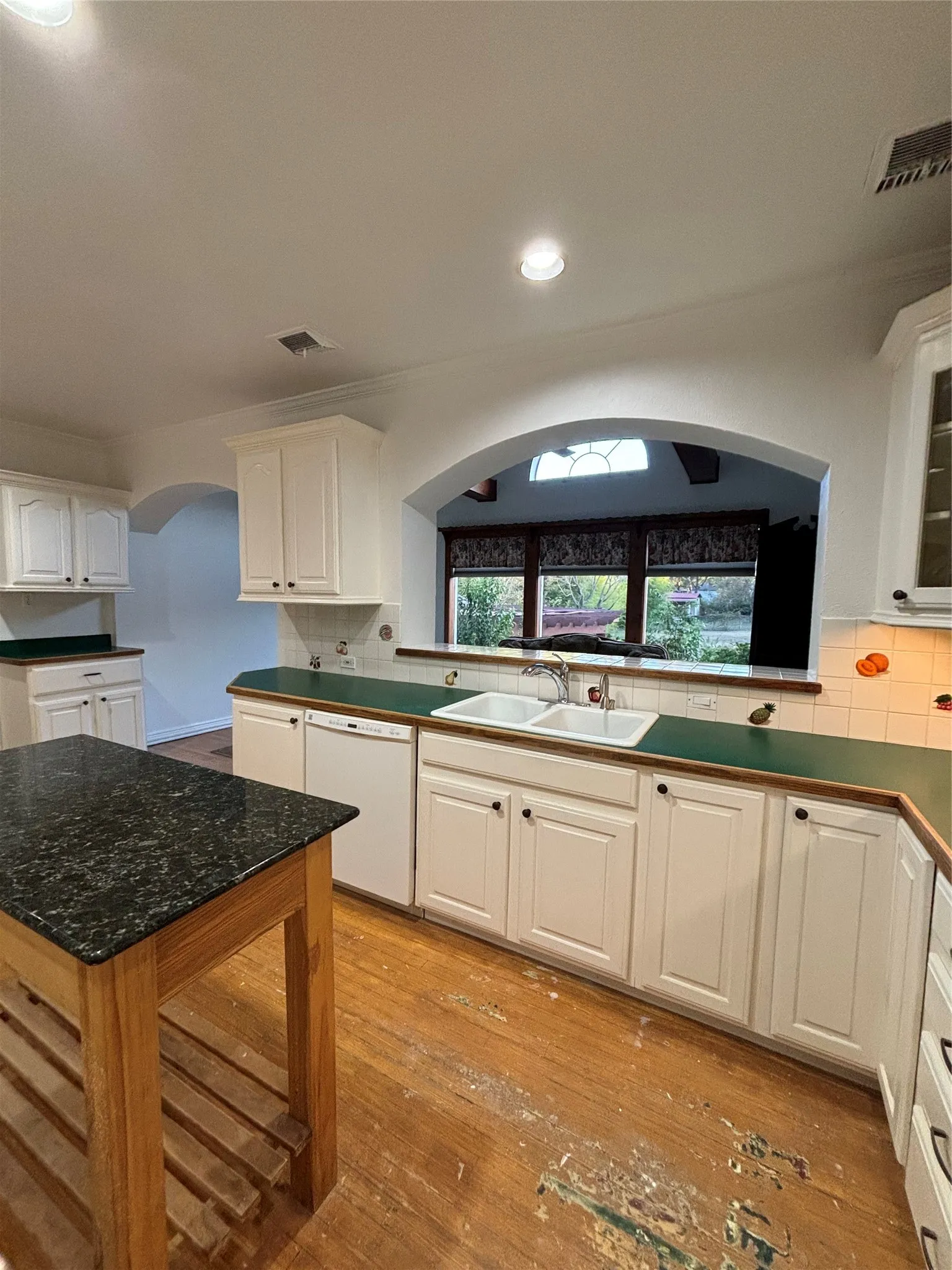 Kitchen featuring white cabinets, light wood-style flooring, backsplash, and recessed lighting