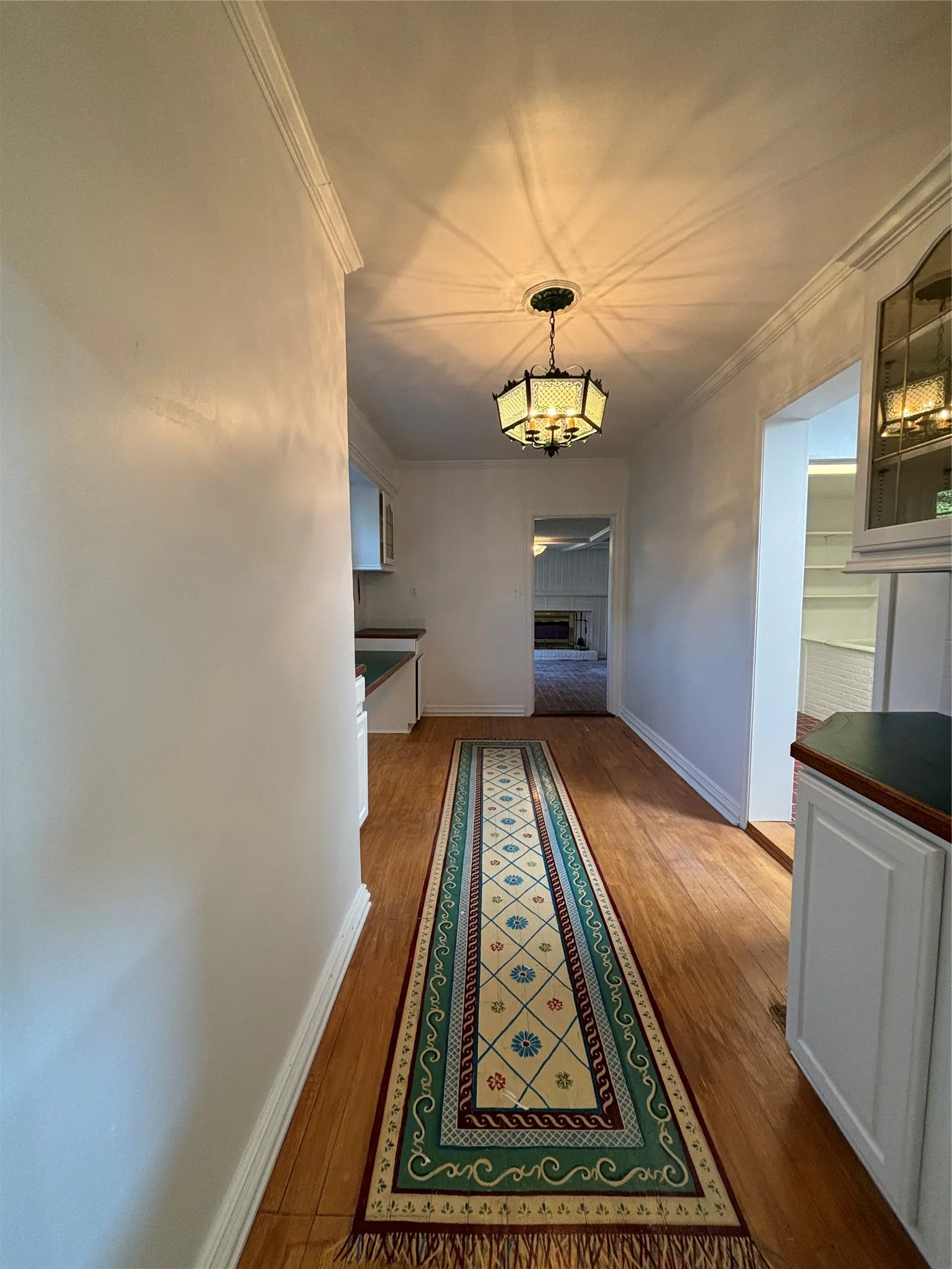Hallway featuring crown molding, wood finished floors, and a chandelier
