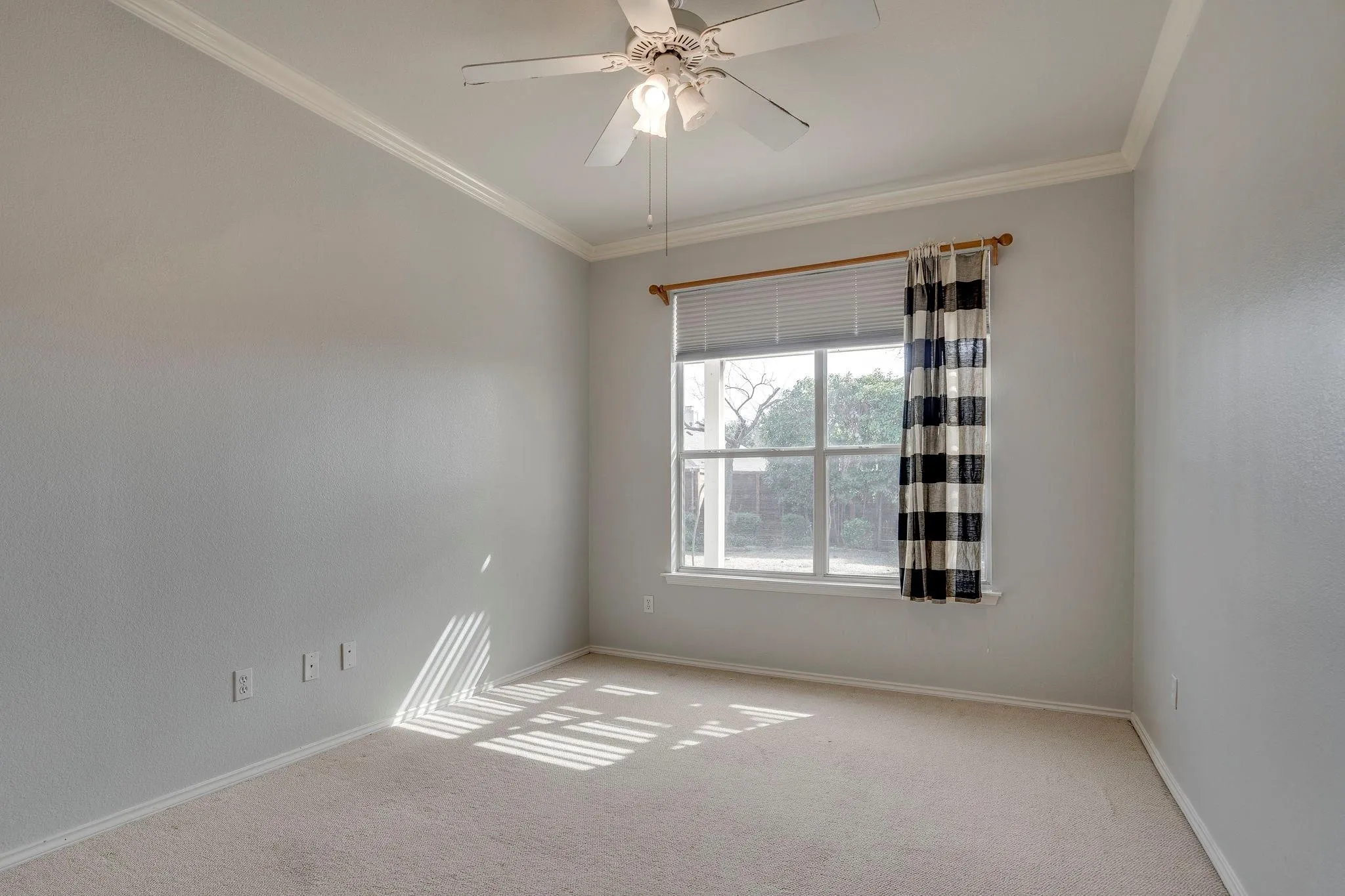 Spacious room featuring neutral carpeting, a large window, and crown molding