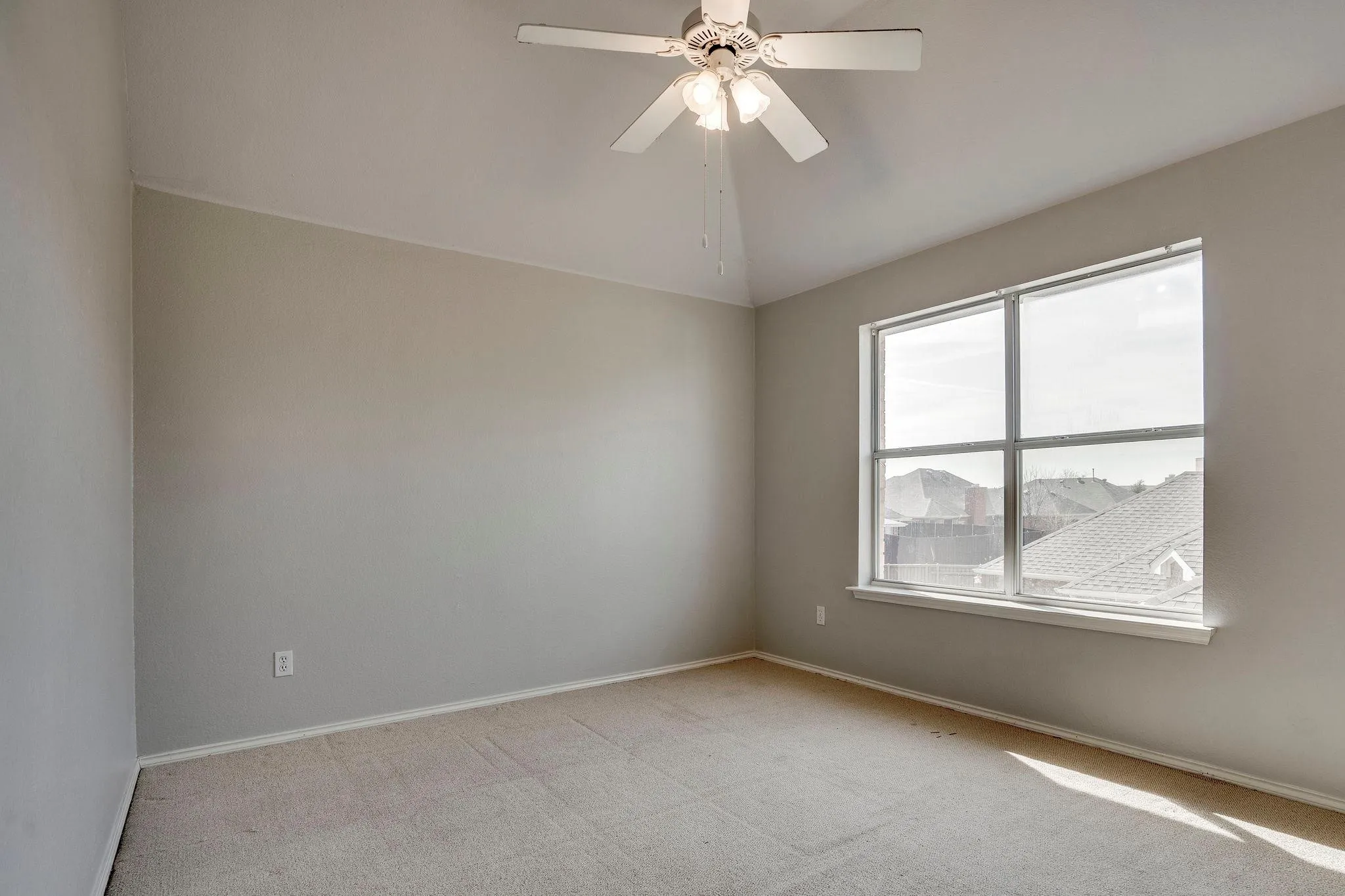 Vaulted ceiling with a ceiling fan, carpeted flooring, and a large window