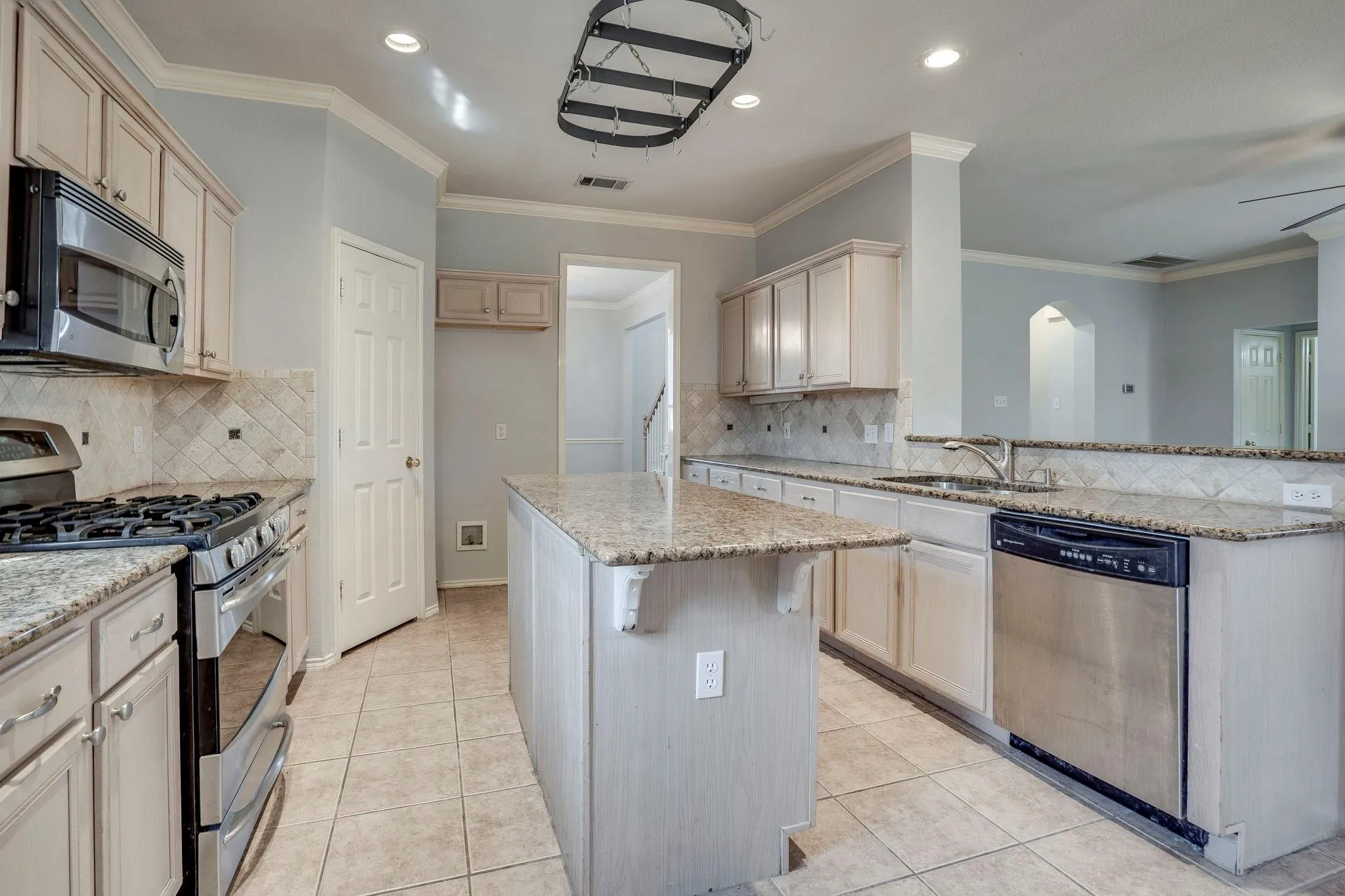 Kitchen featuring a central island, tile flooring, light-toned cabinetry, and stainless steel appliances