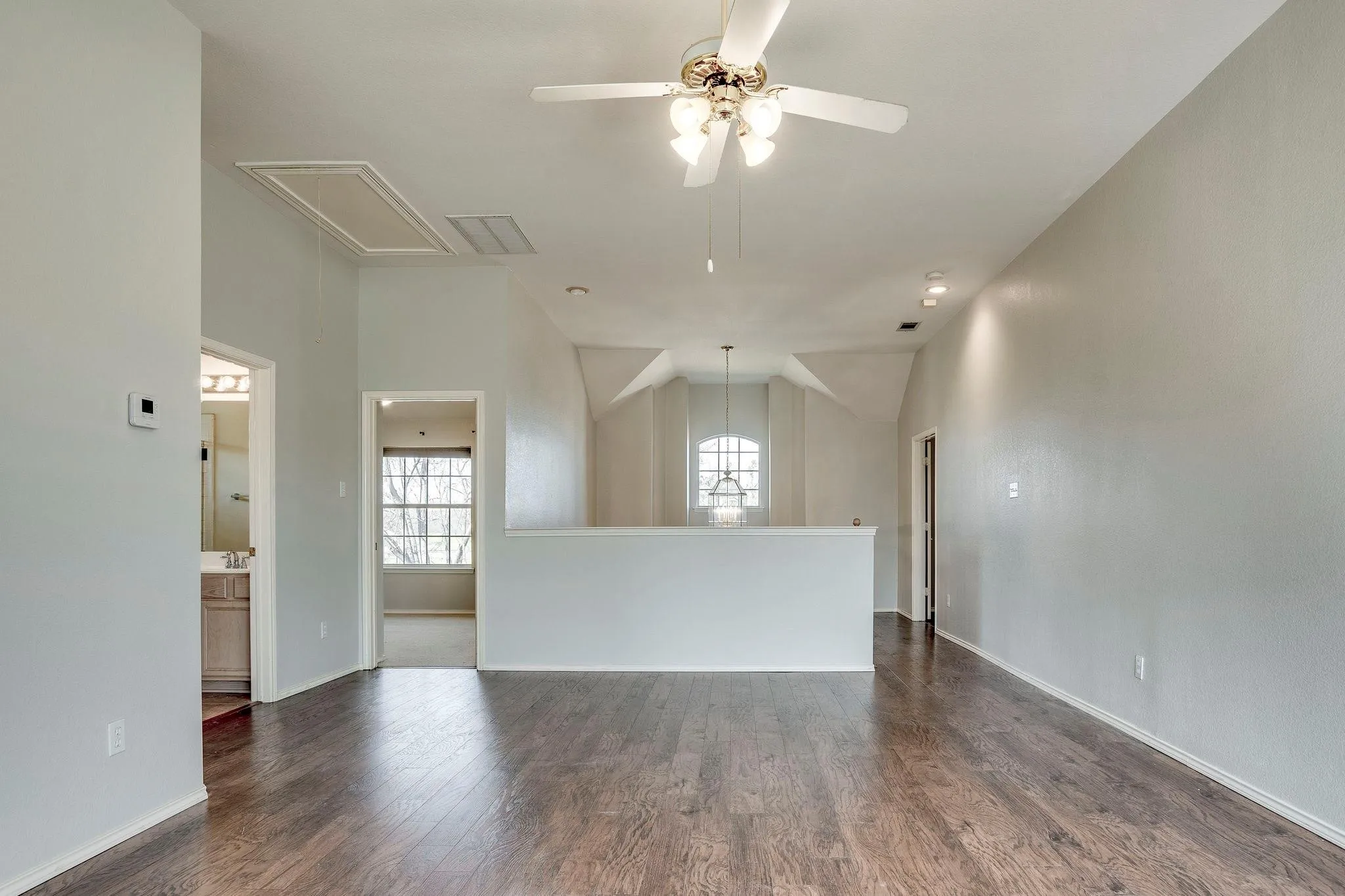 Wood-finish flooring throughout, ceiling fan with integrated lighting, recessed lighting, and a half-wall partition