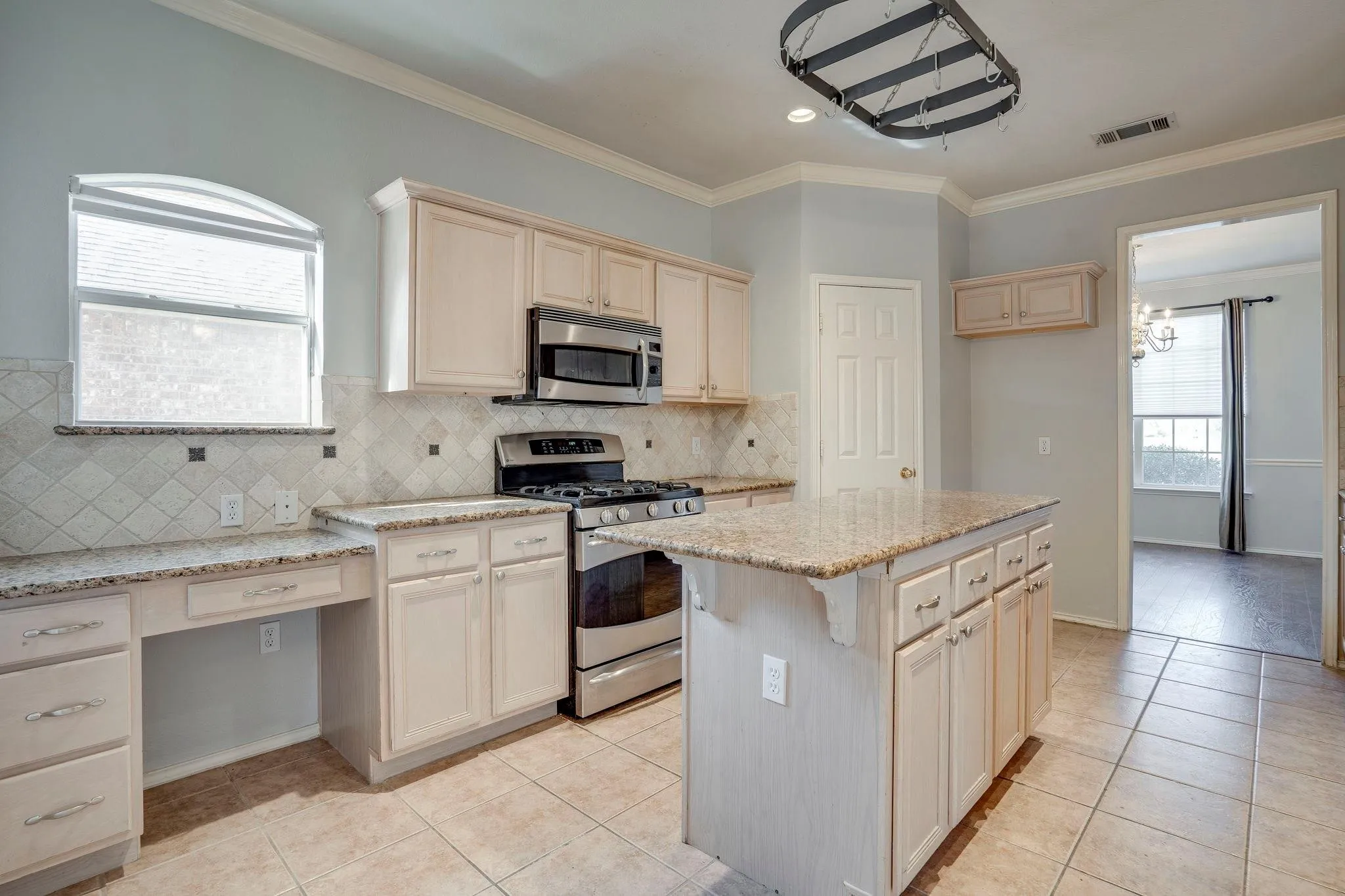 Kitchen featuring a central island with countertop, tile flooring, stainless steel appliances, and built-in cabinetry