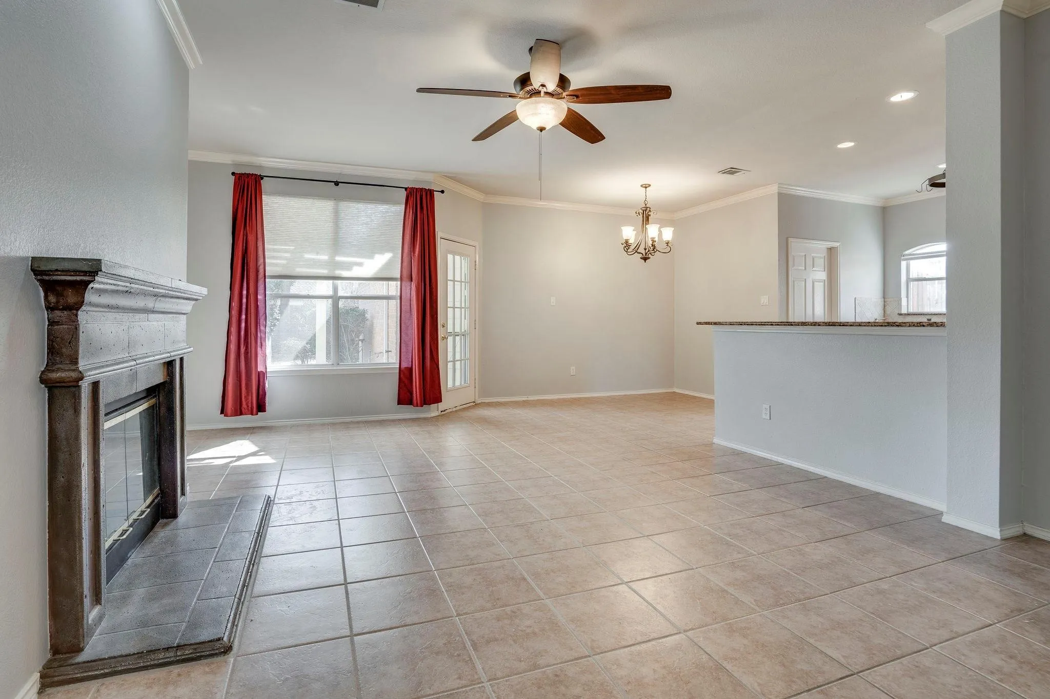 Spacious room featuring tile flooring, a fireplace with a wood mantel, and crown molding