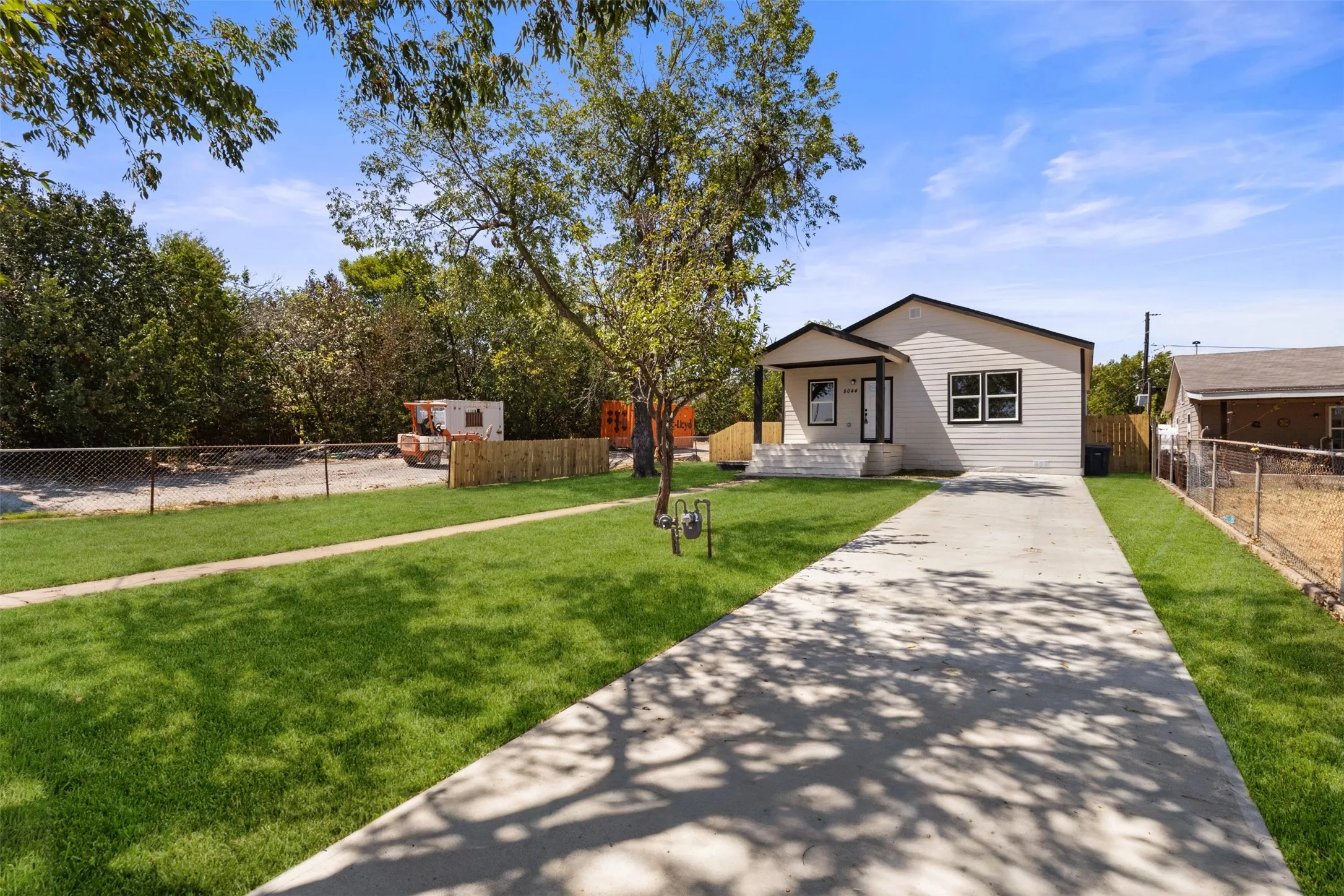 Single-story residence featuring light-colored siding, a covered porch with dark trim, and a concrete driveway